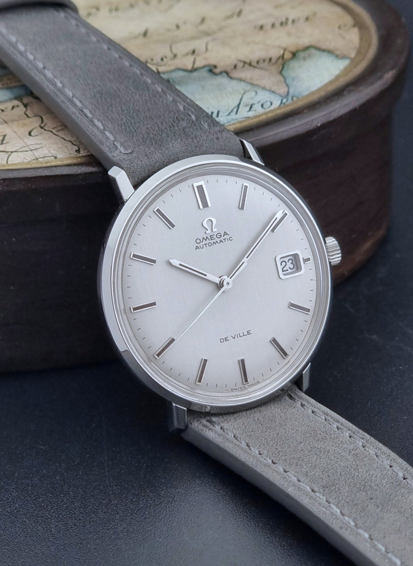 Vintage Omega Wristwatch De-Ville 166.033 with gray strap on a dark background side view