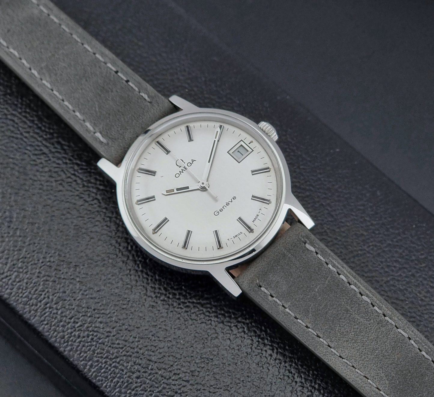 Vintage Omega watch Geneve 135.070 with grey leather strap on a dark surface
