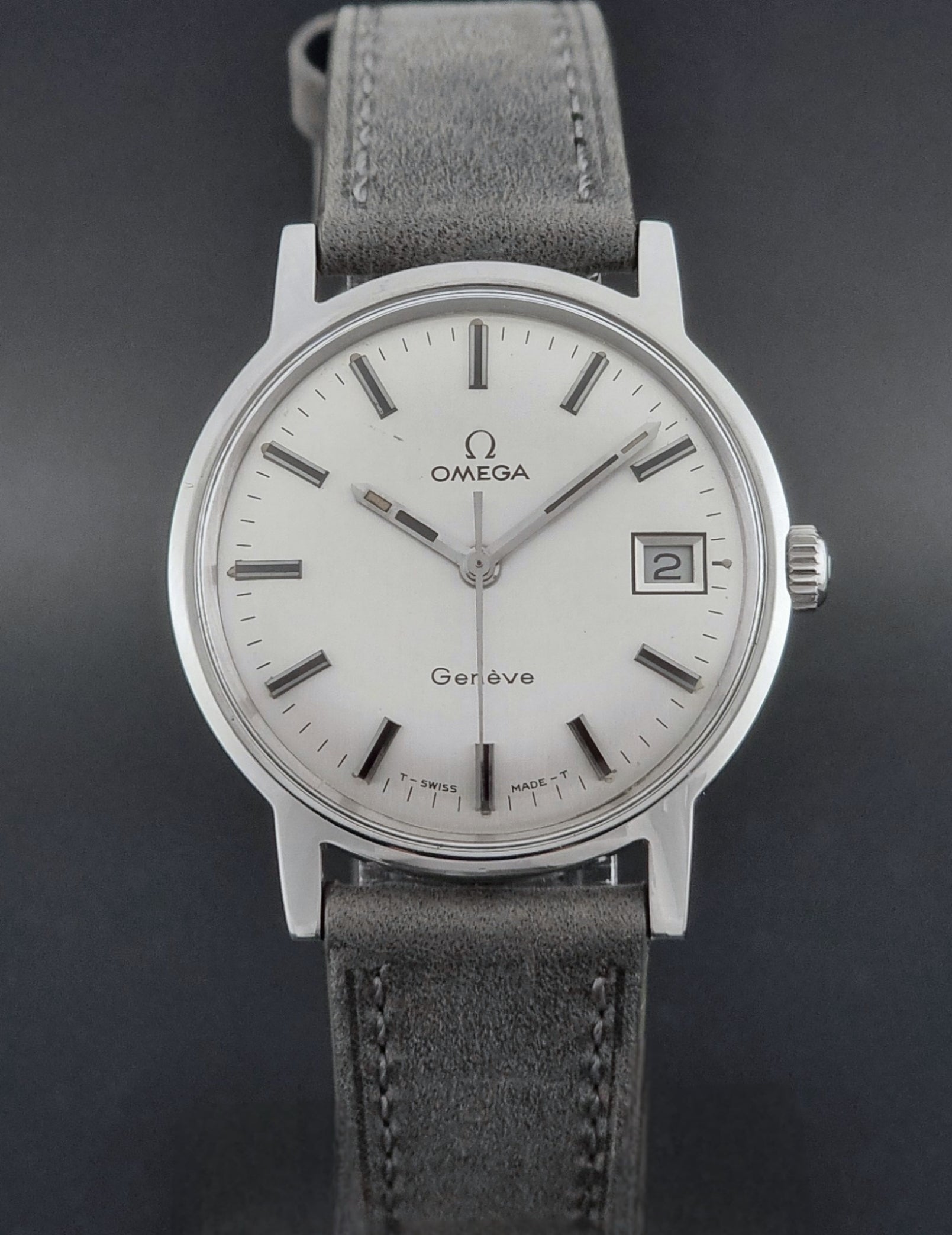 Vintage Omega watch Geneve 135.070 with grey leather strap on a dark surface close front view