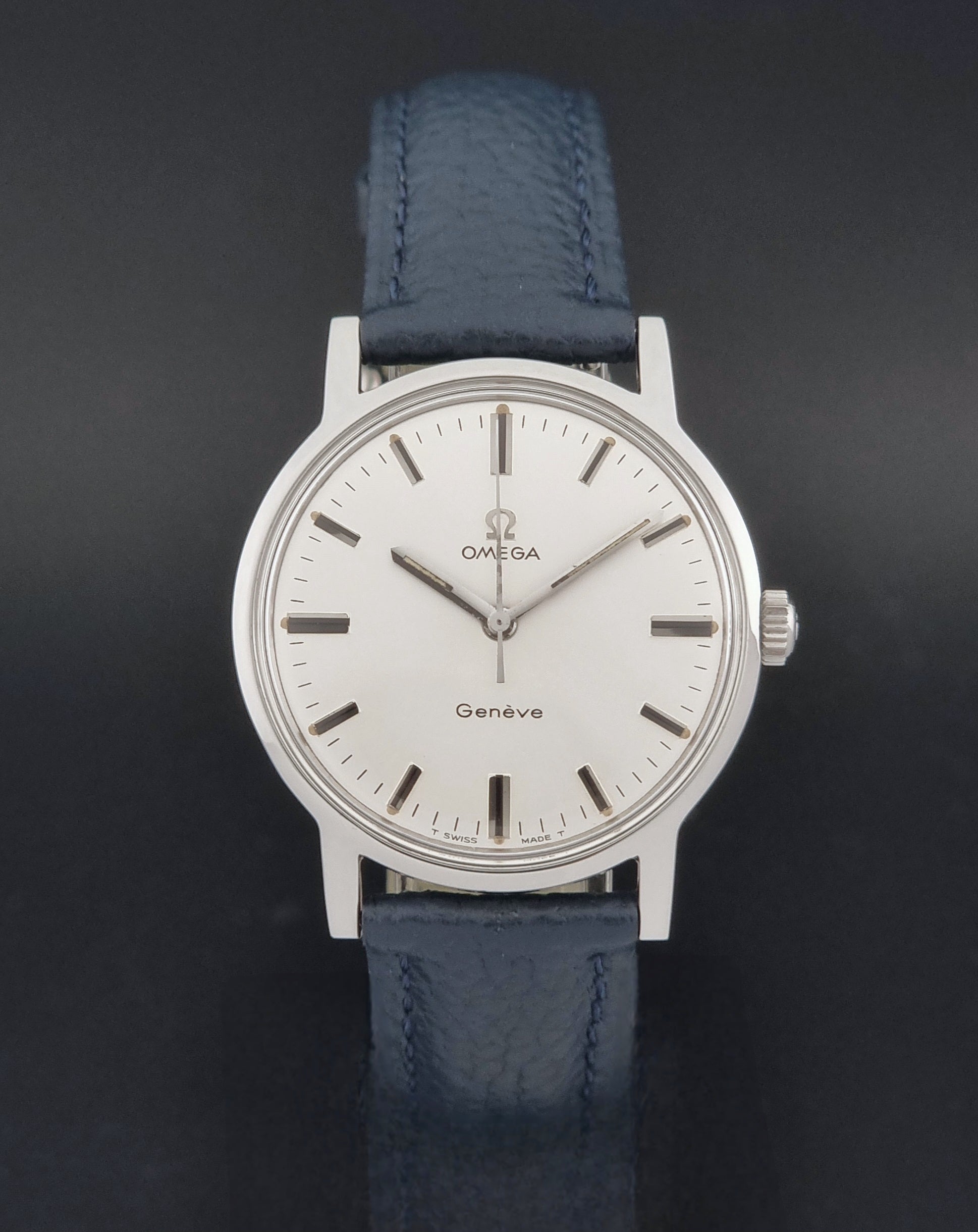 Vintage Omega Geneve 135.070 watch with a blue leather strap on a gray background close dial view