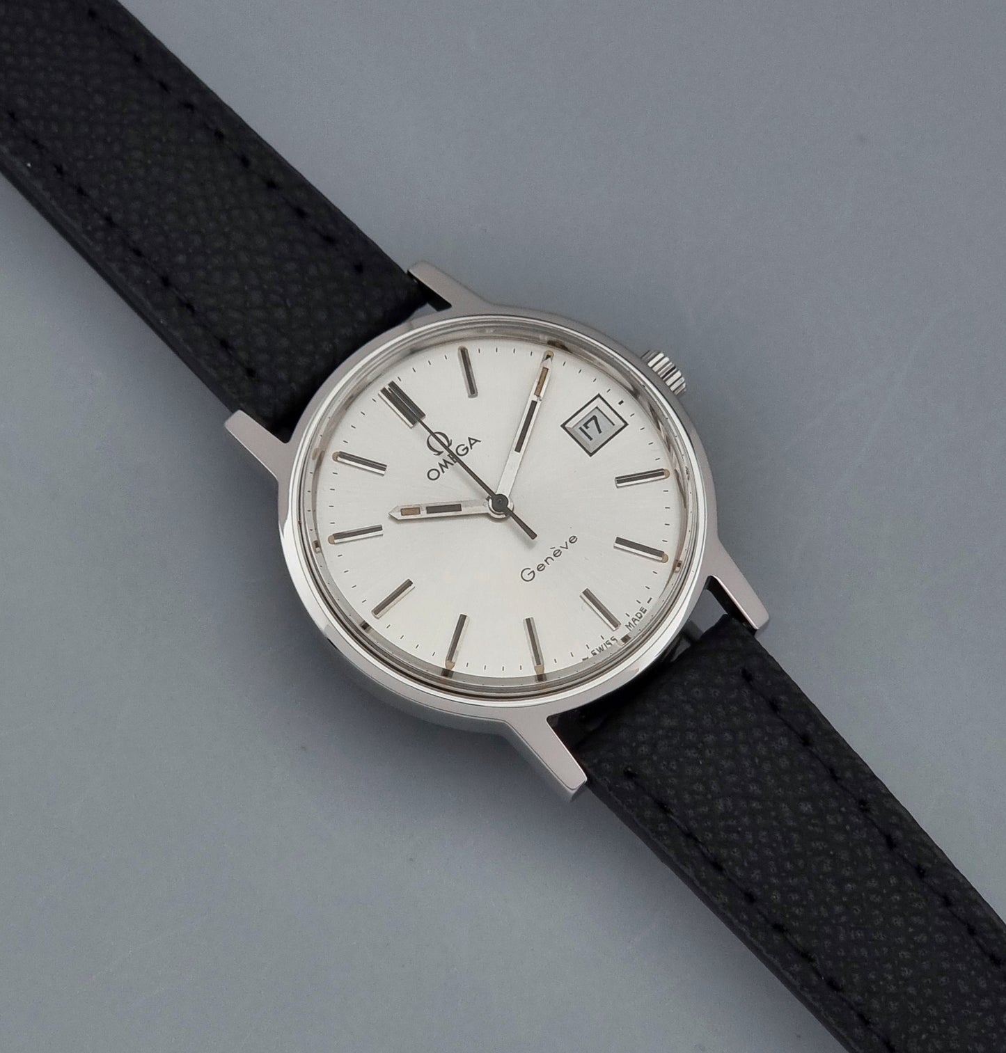Vintage Omega Geneve 136.0098 Wristwatch with black strap and silver case on a gray background dial