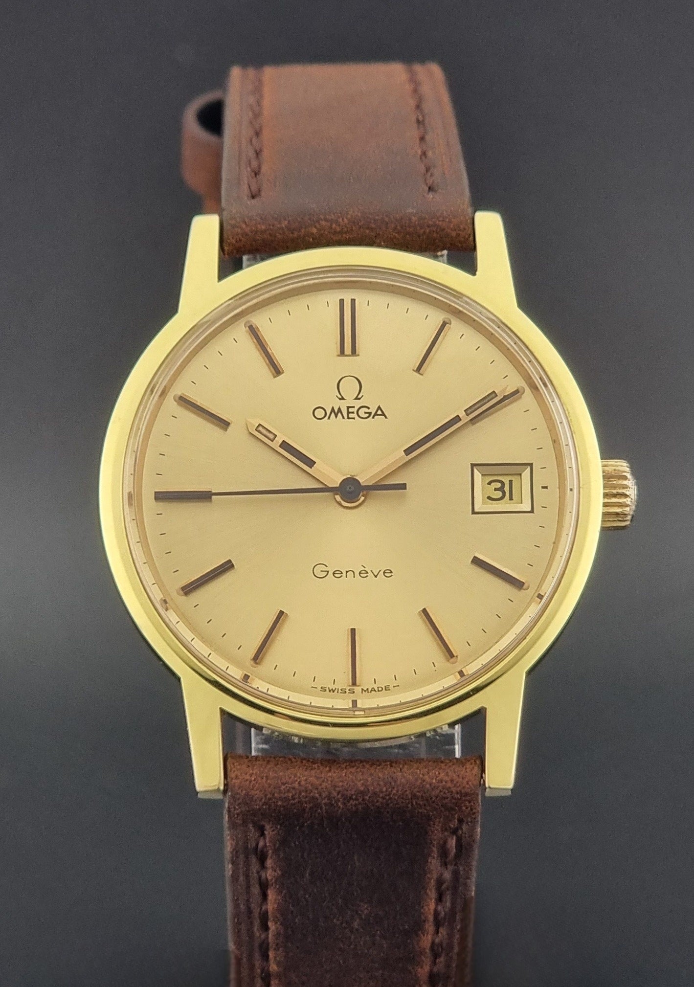 Vintage Omega Wristwatch Geneve 136.0098 with brown leather strap on a green surface dial view