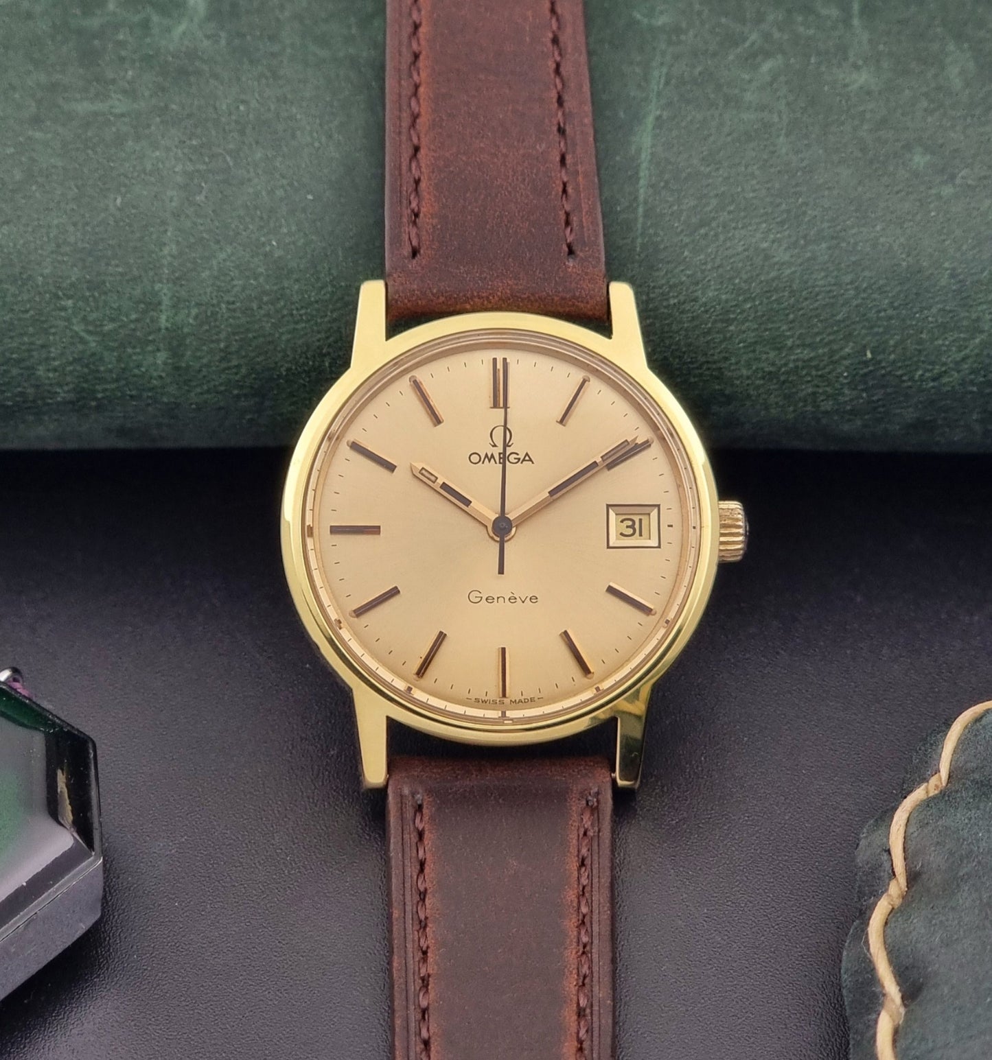 Vintage Omega Wristwatch Geneve 136.0098 with brown leather strap on a green surface front view