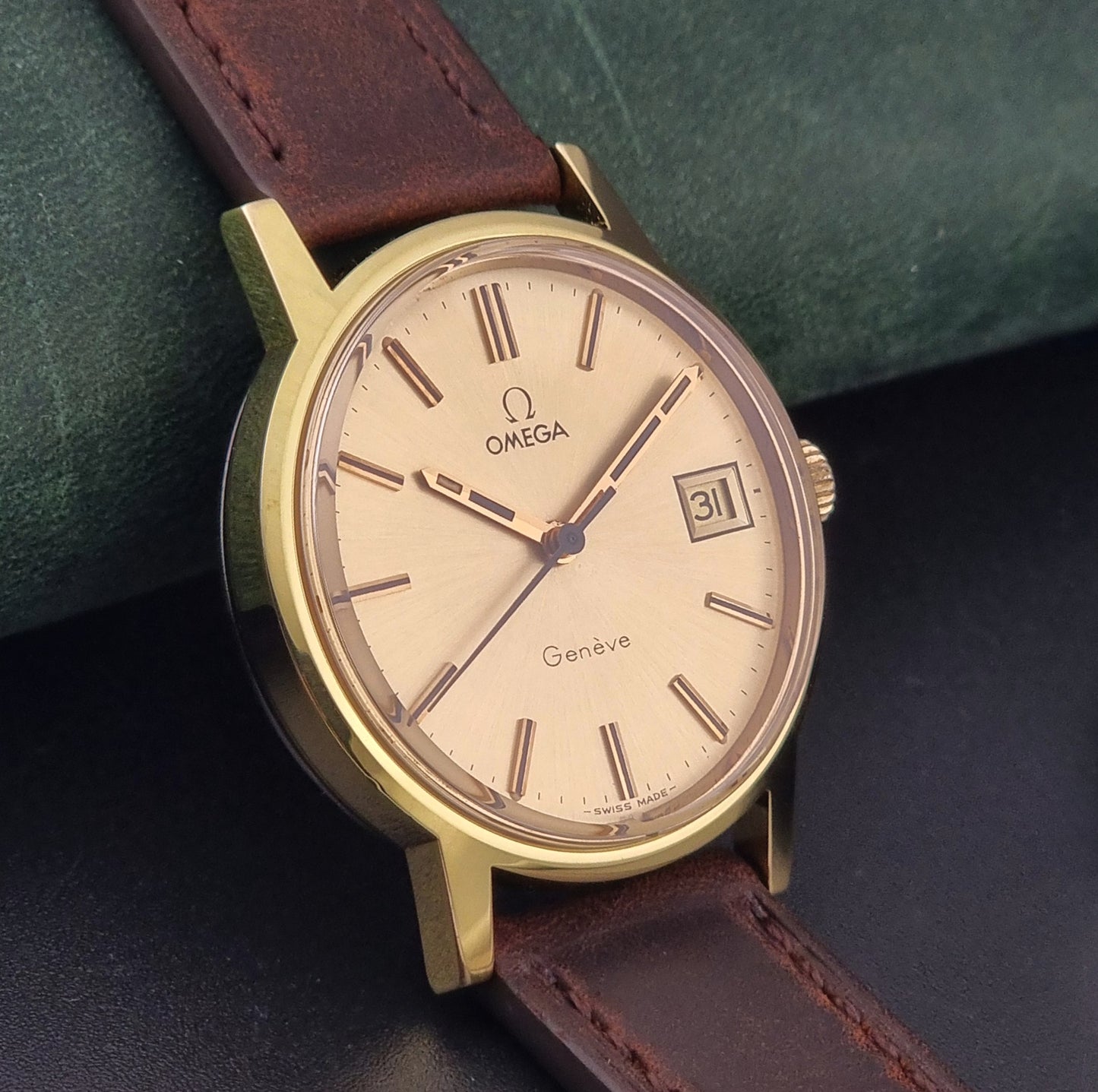 Vintage Omega Wristwatch Geneve 136.0098 with brown leather strap on a green surface side view