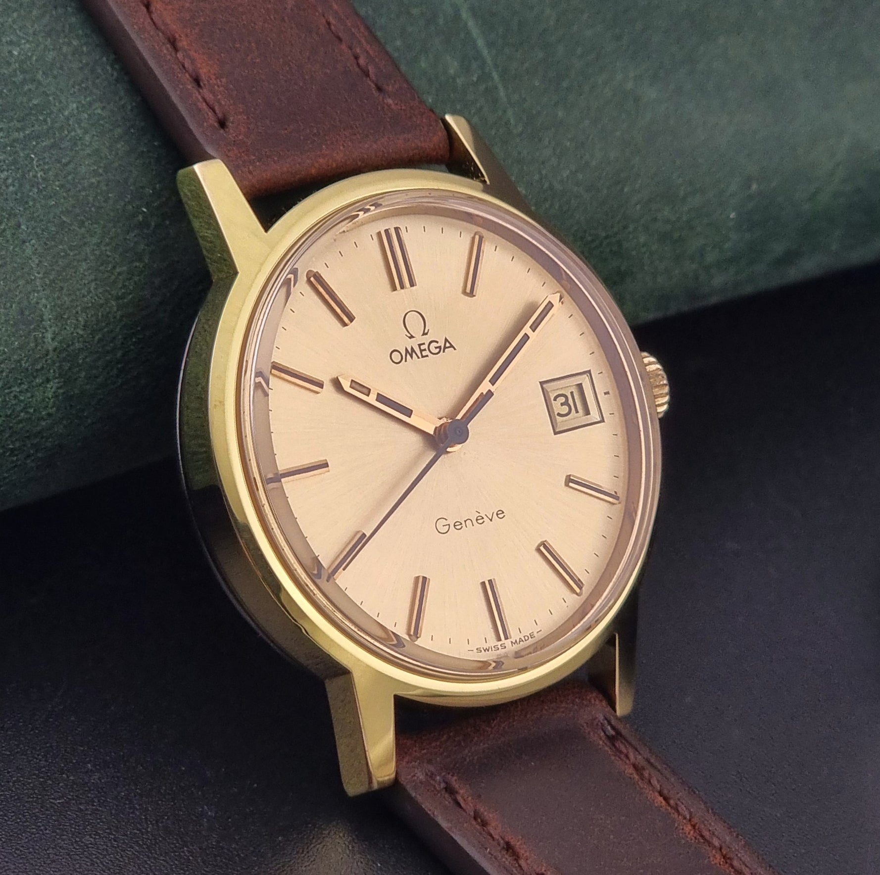 Vintage Omega Wristwatch Geneve 136.0098 with brown leather strap on a green surface side view