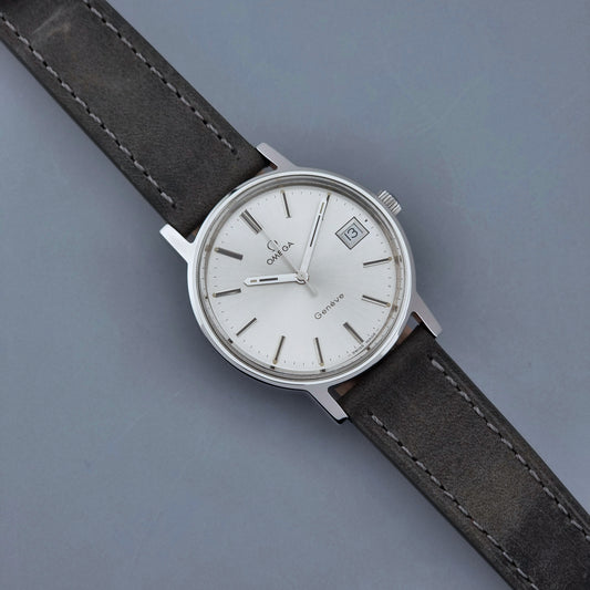 Vintage Omega Wristwatch Geneve 136.0099 with a grey leather strap on a grey background front