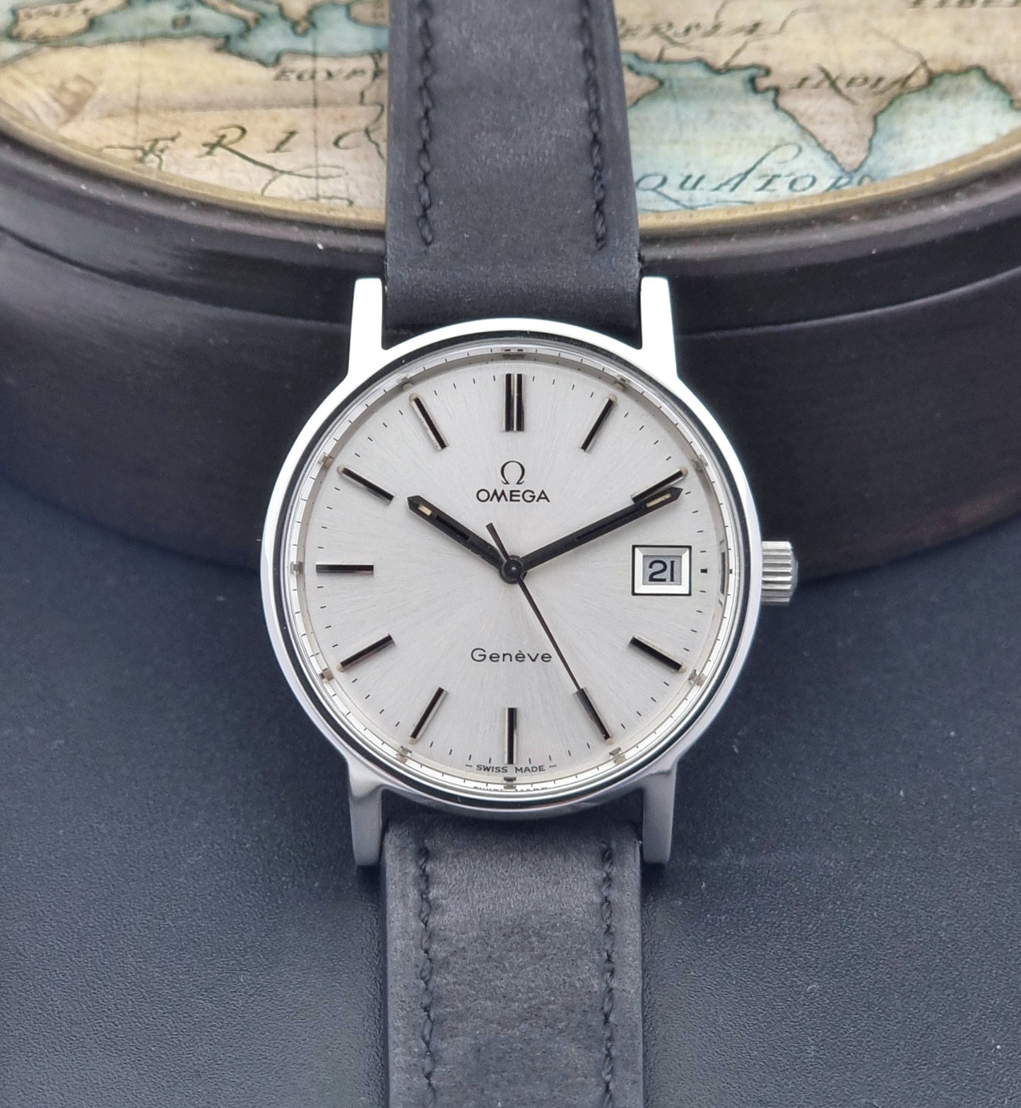 Vintage Omega Wristwatch Geneve 136.0099 with a black leather strap on a dark surface dial view