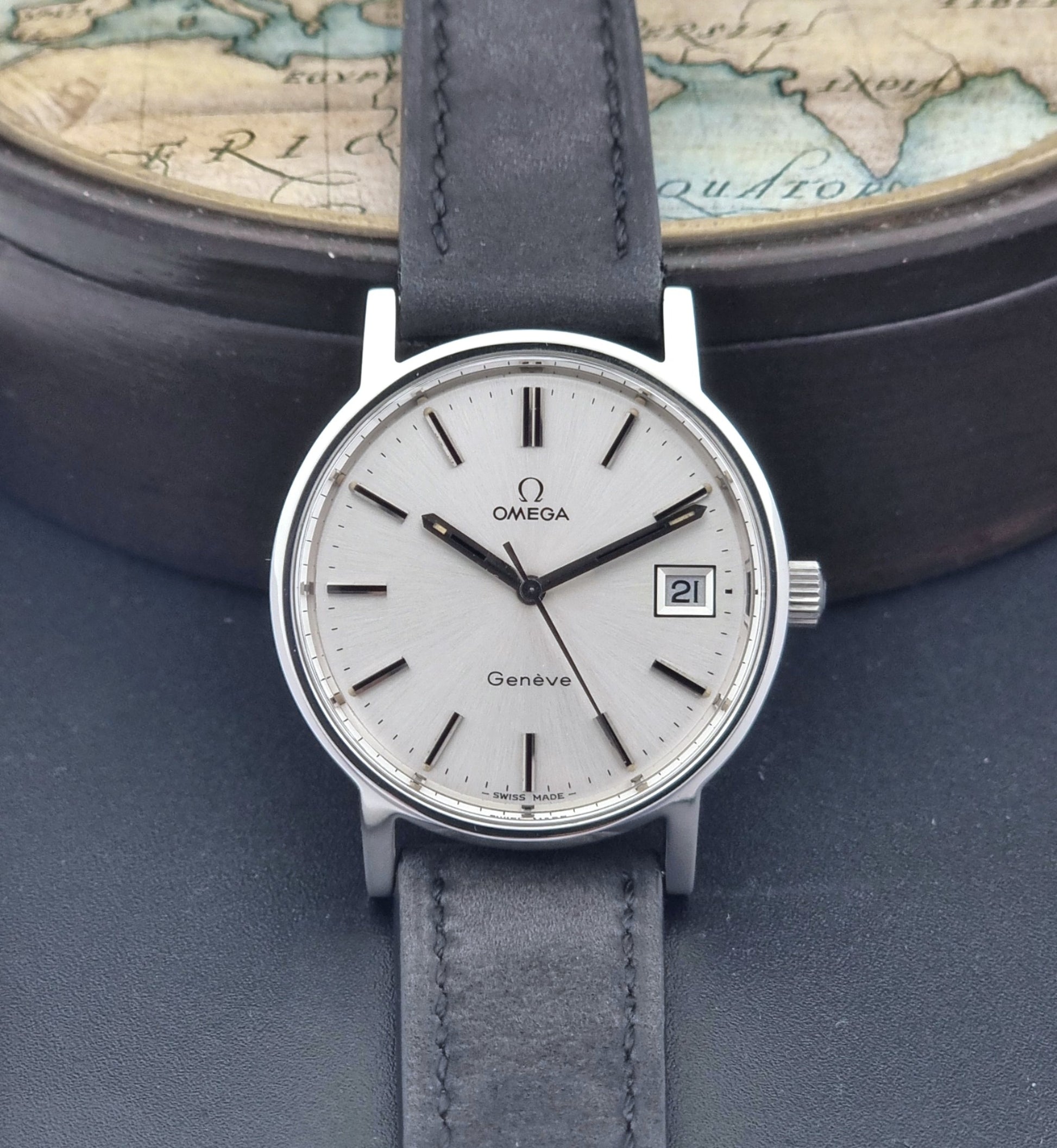 Vintage Omega Wristwatch Geneve 136.0099 with a black leather strap on a dark surface dial view