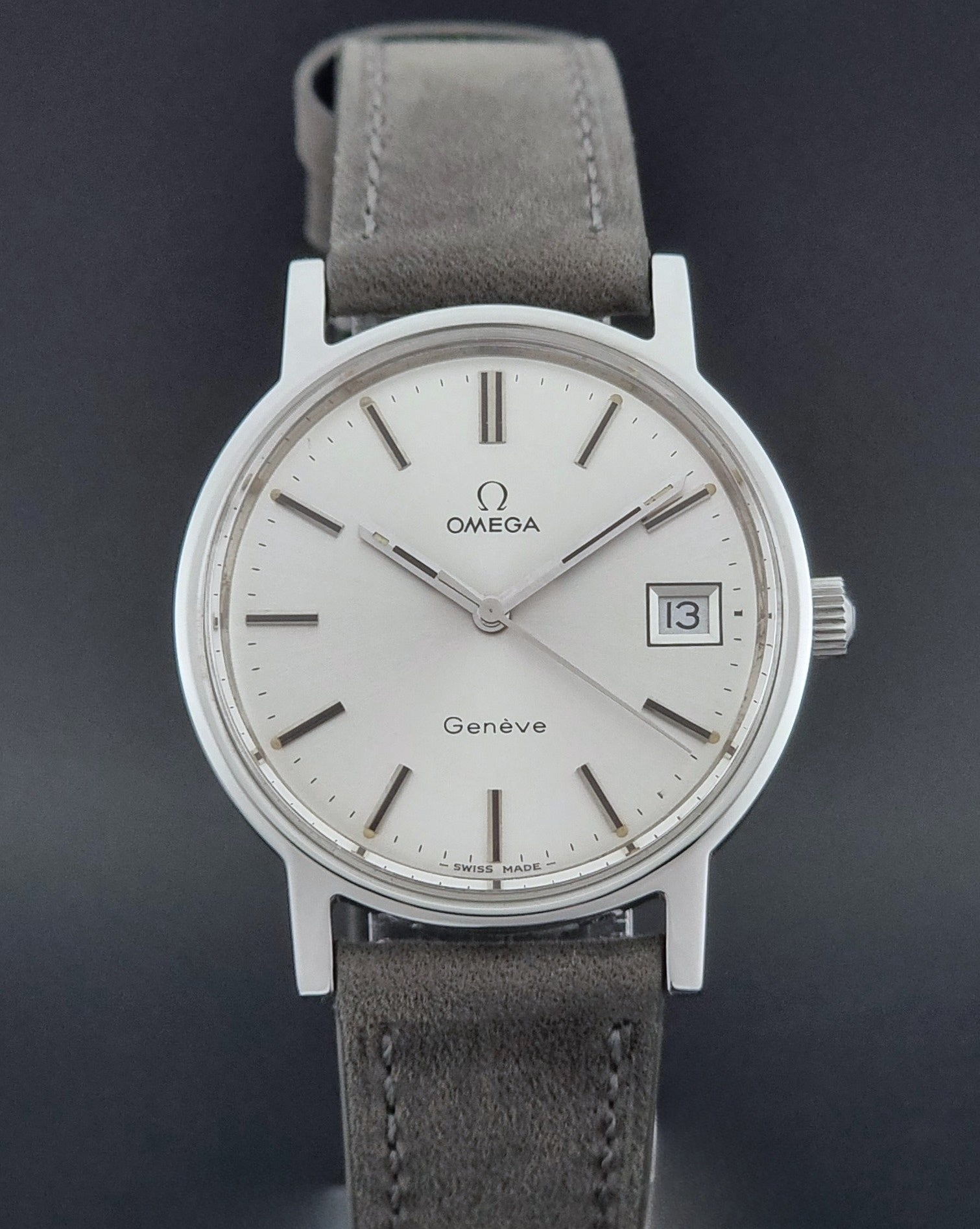 Vintage Omega Wristwatch Geneve 136.0099 with a grey leather strap on a grey background dial view