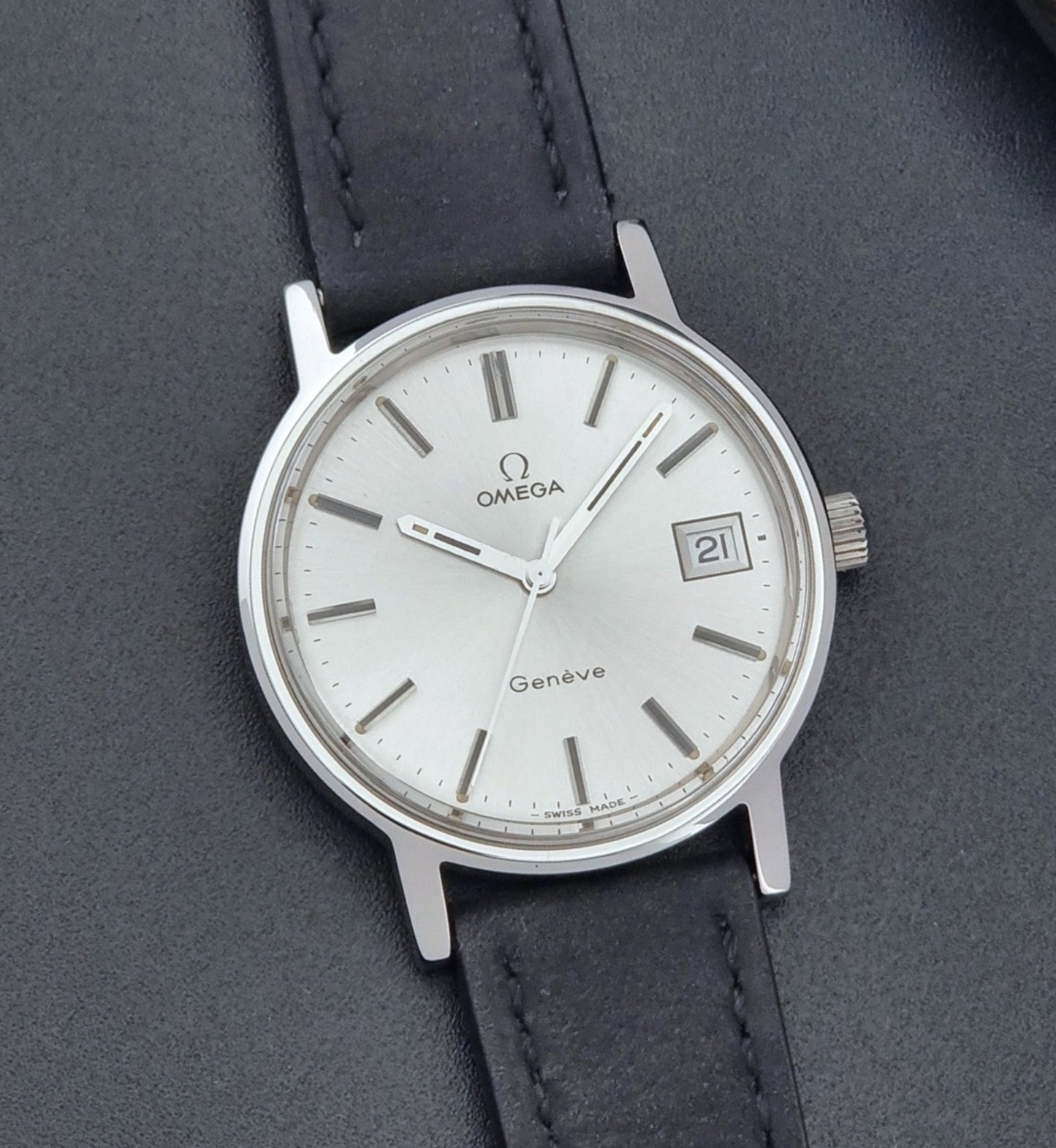 Vintage Omega Wristwatch Geneve 136.0099 with a black leather strap on a dark surface front view
