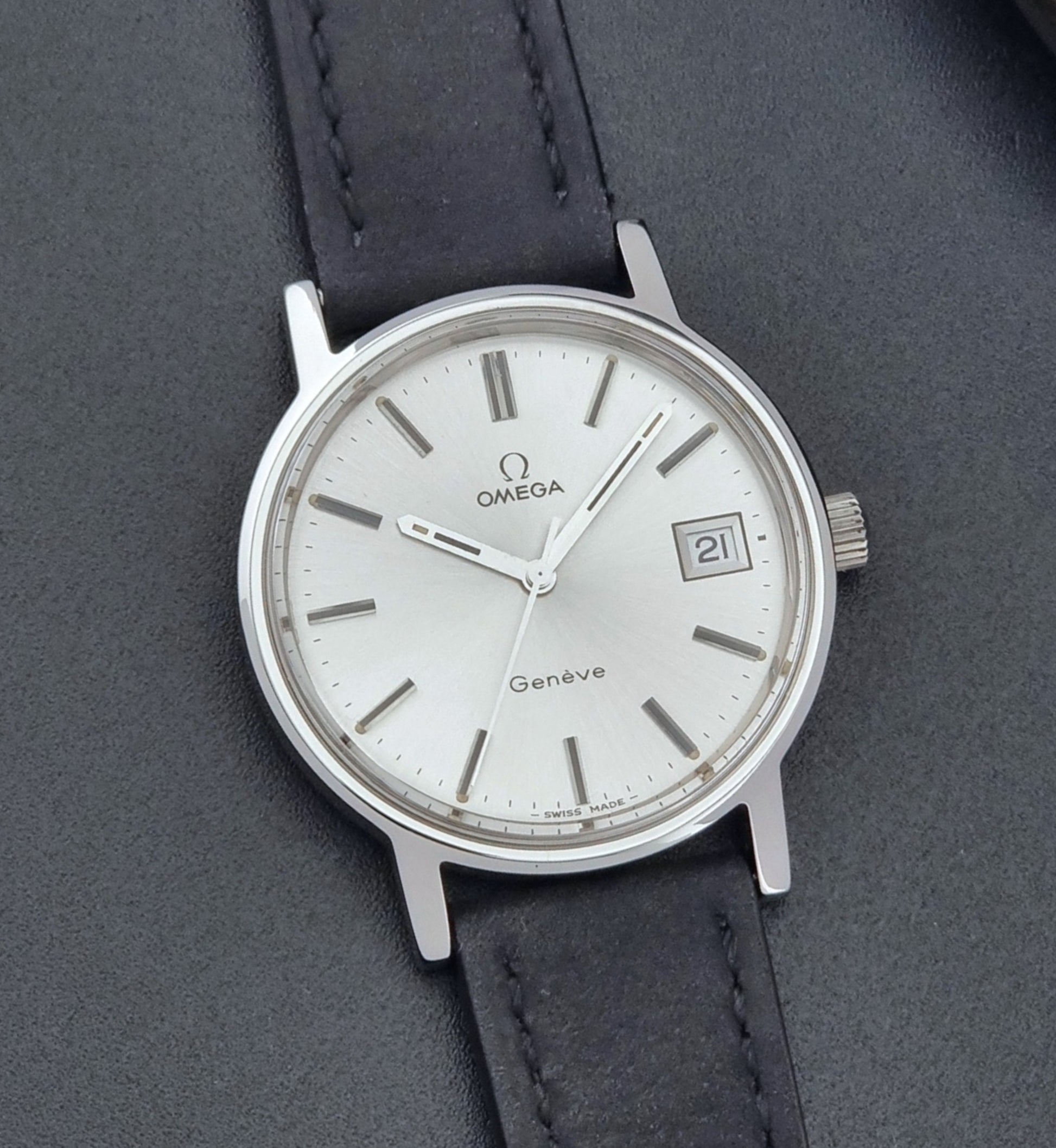 Vintage Omega Wristwatch Geneve 136.0099 with a black leather strap on a dark surface front view