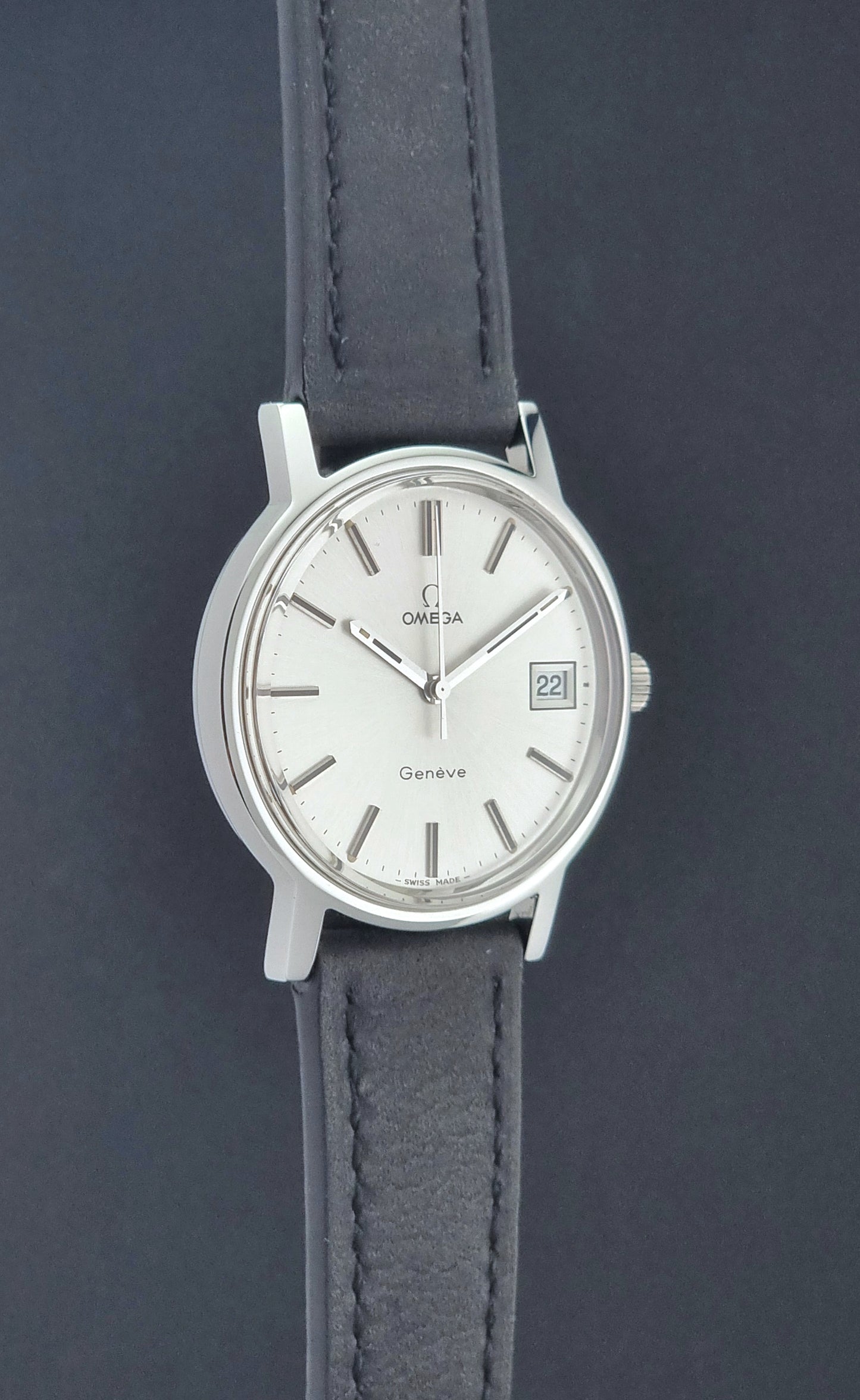 Vintage Omega Wristwatch Geneve 136.0099 with a black leather strap on a dark surface side profile view