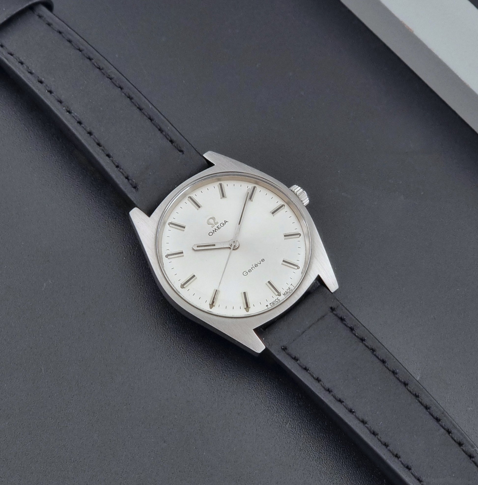 Vintage Omega watch Geneve 136.041 with a black leather strap on a dark gray background dial