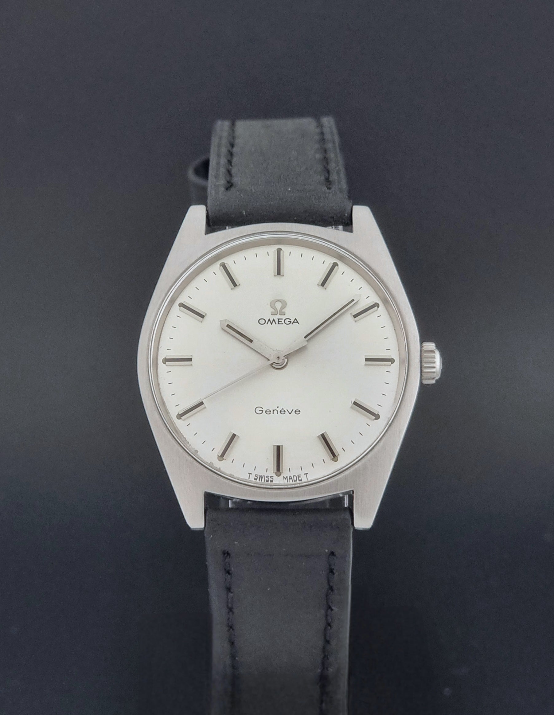 Vintage Omega watch Geneve 136.041 with a black leather strap on a dark gray background close dial view