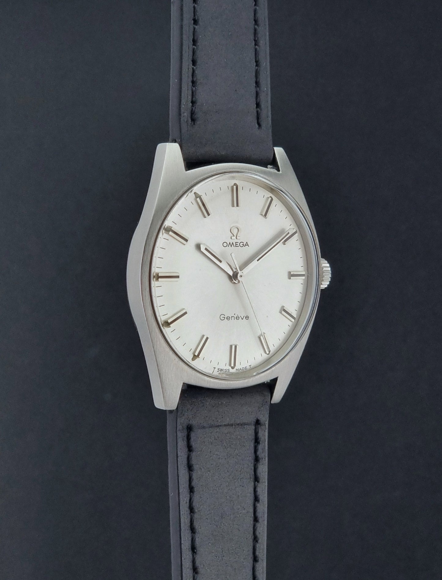 Vintage Omega watch Geneve 136.041 with a black leather strap on a dark gray background side profile view