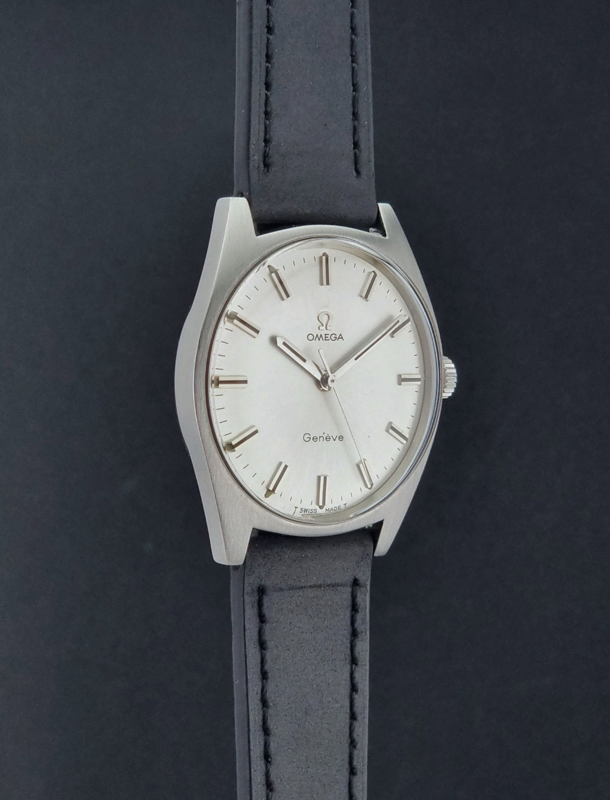 Vintage Omega watch Geneve 136.041 with a black leather strap on a dark gray background side profile view