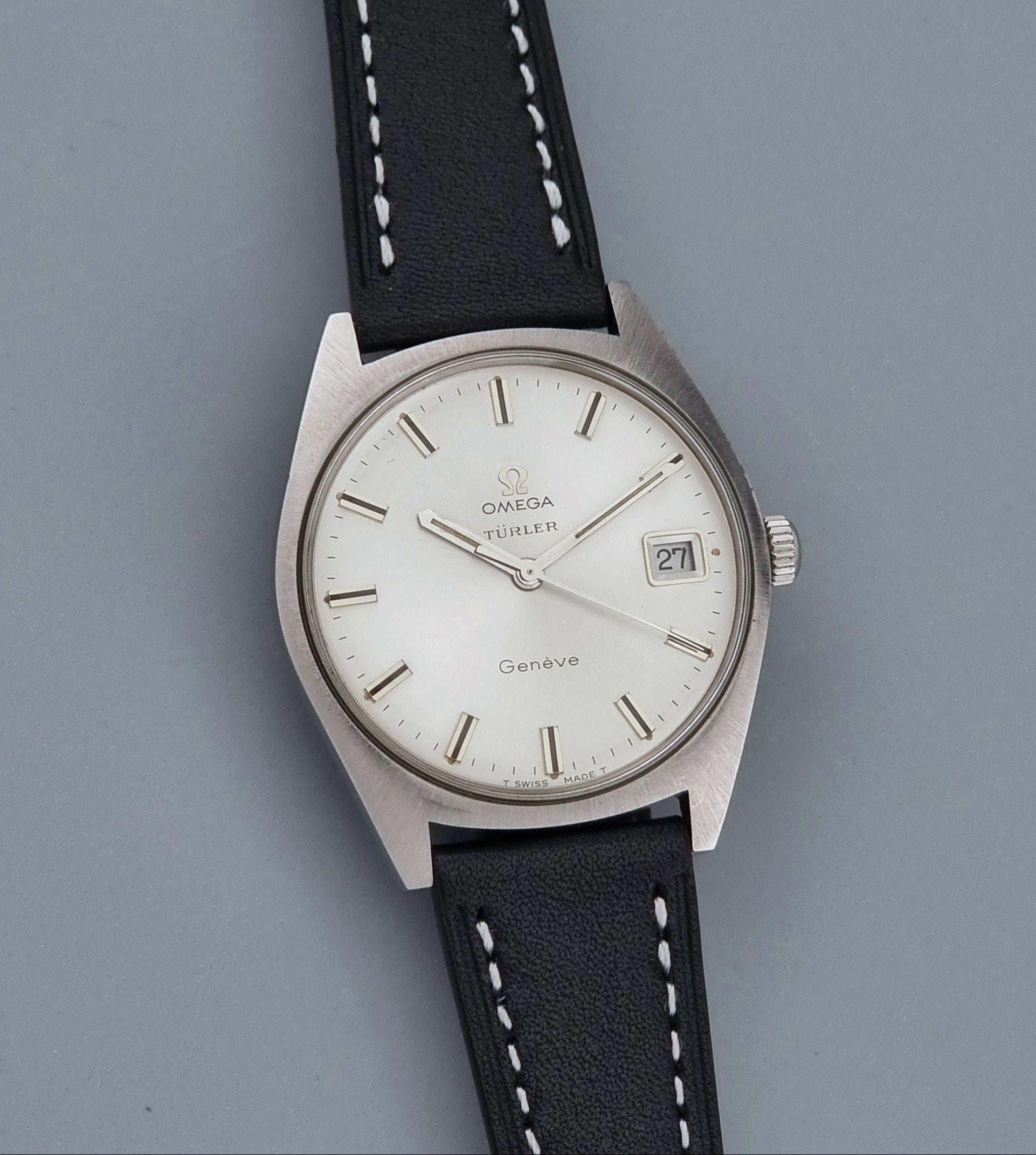 Vintage Omega watch Geneve 136.041 Co-signed Türler with a stainless steel case,  and a black leather strap with white stitching, shown on a gray background front view