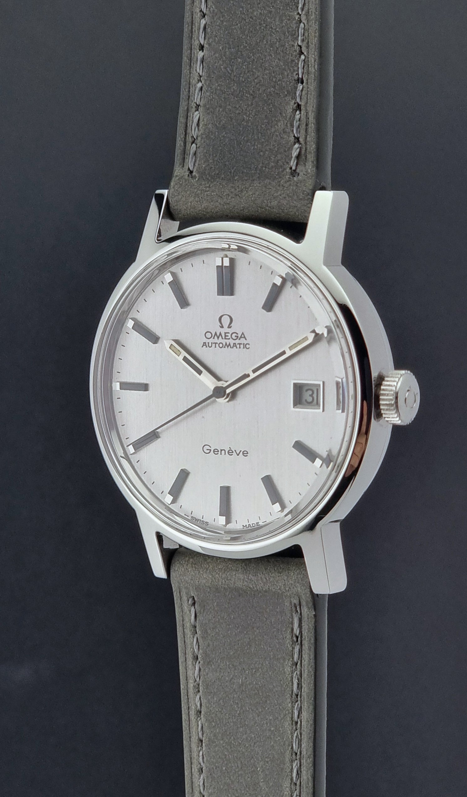 Vintage Omega Wristwatch Geneve 166.0098 with grey leather strap on a dark textured surface crown profile view
