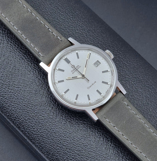 Vintage Omega Wristwatch Geneve 166.0098 with grey leather strap on a dark textured surface front