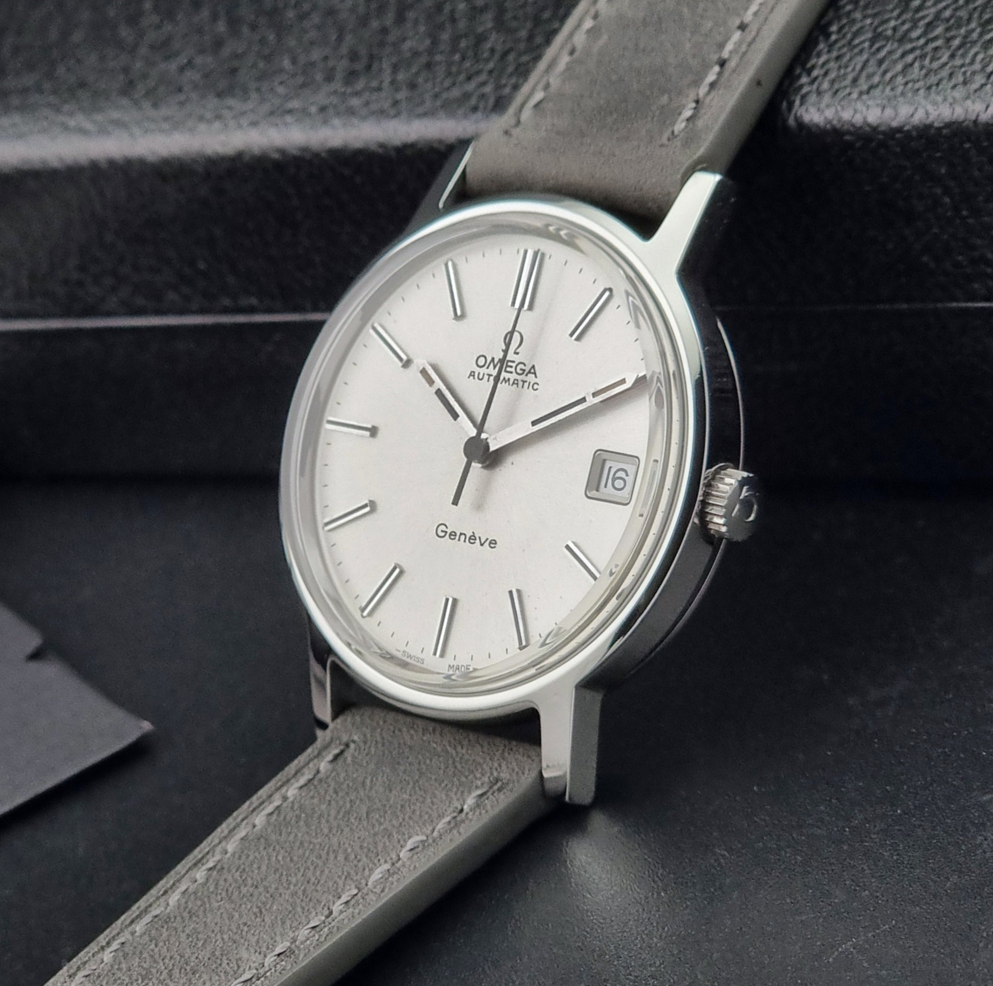 Vintage Omega watch with gray leather strap on a dark background