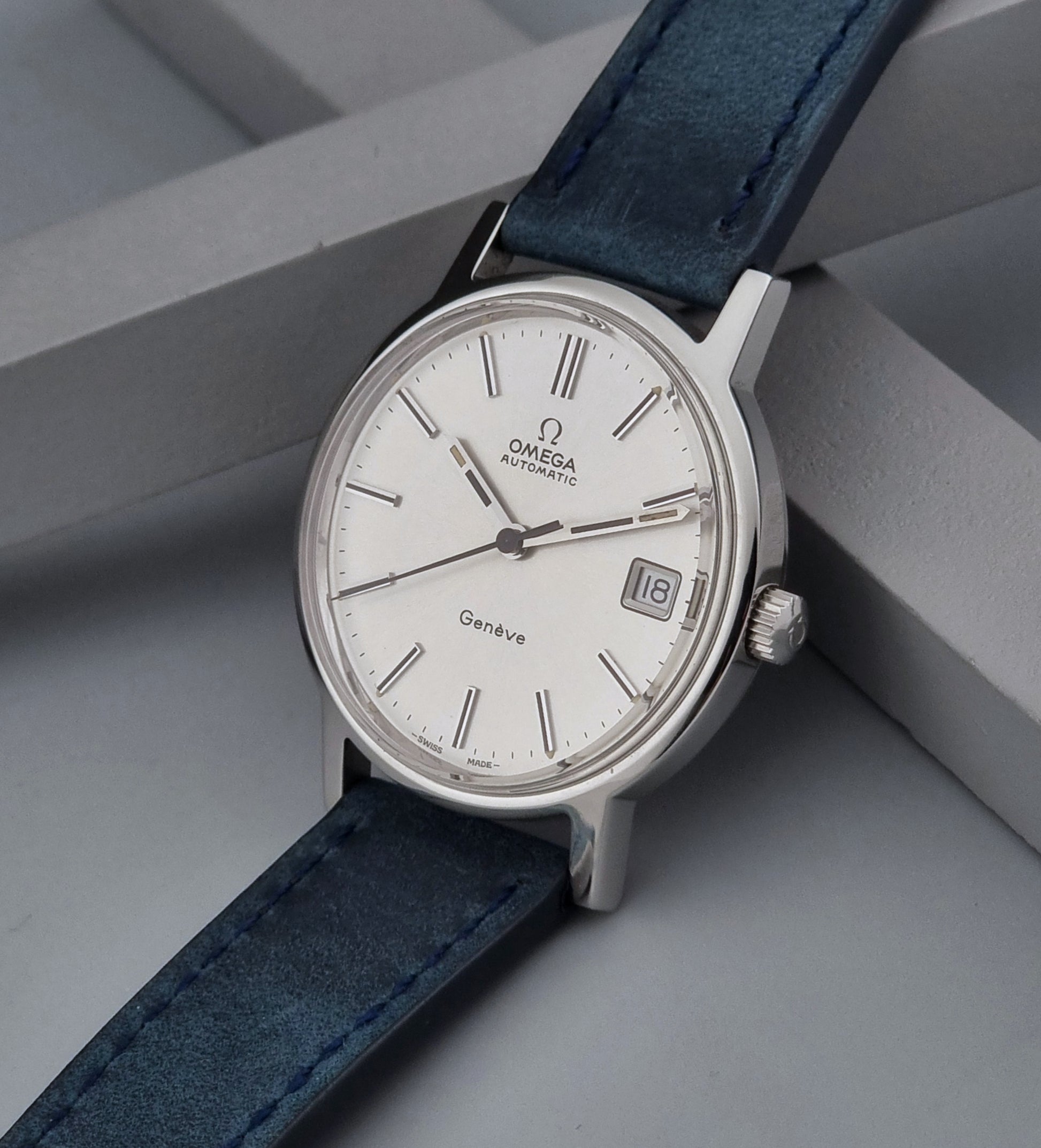 Vintage Omega Geneve 166.0163 wristwatch with blue strap on a gray surface