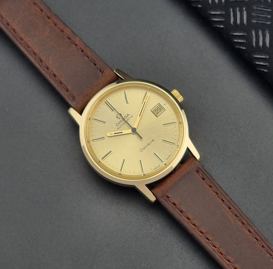 Vintage Omega Wristwatch Geneve 166.0163 gold watch with brown leather strap on a dark surface dial