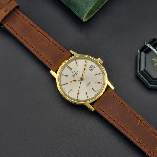 Vintage Omega Wristwatch Geneve 166.0163 with brown leather strap and gold case on a dark surface dial