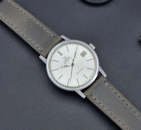 Vintage Omega Geneve 166.0163 watch with gray leather strap on a dark background dial