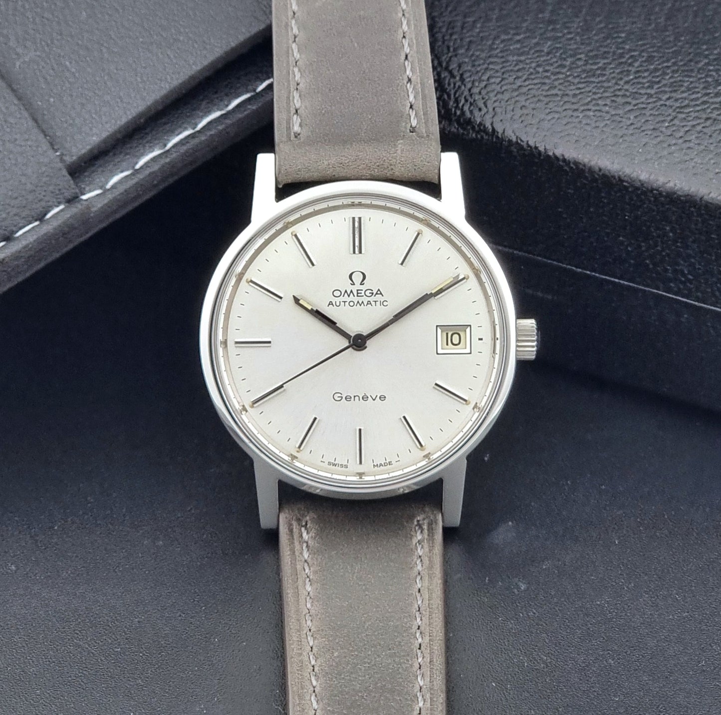 Vintage Omega Geneve 166.0163 watch with gray leather strap on a dark background dial view