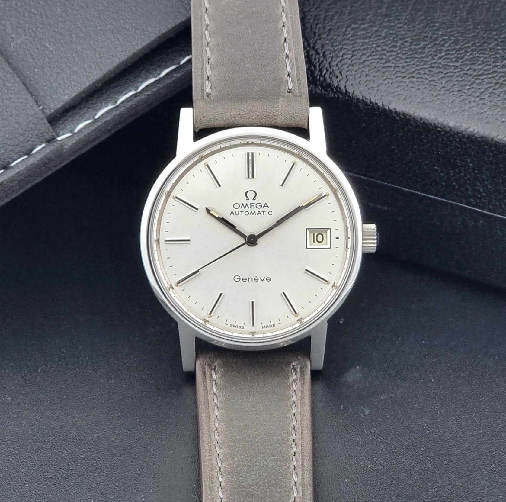 Vintage Omega Geneve 166.0163 watch with gray leather strap on a dark background dial view