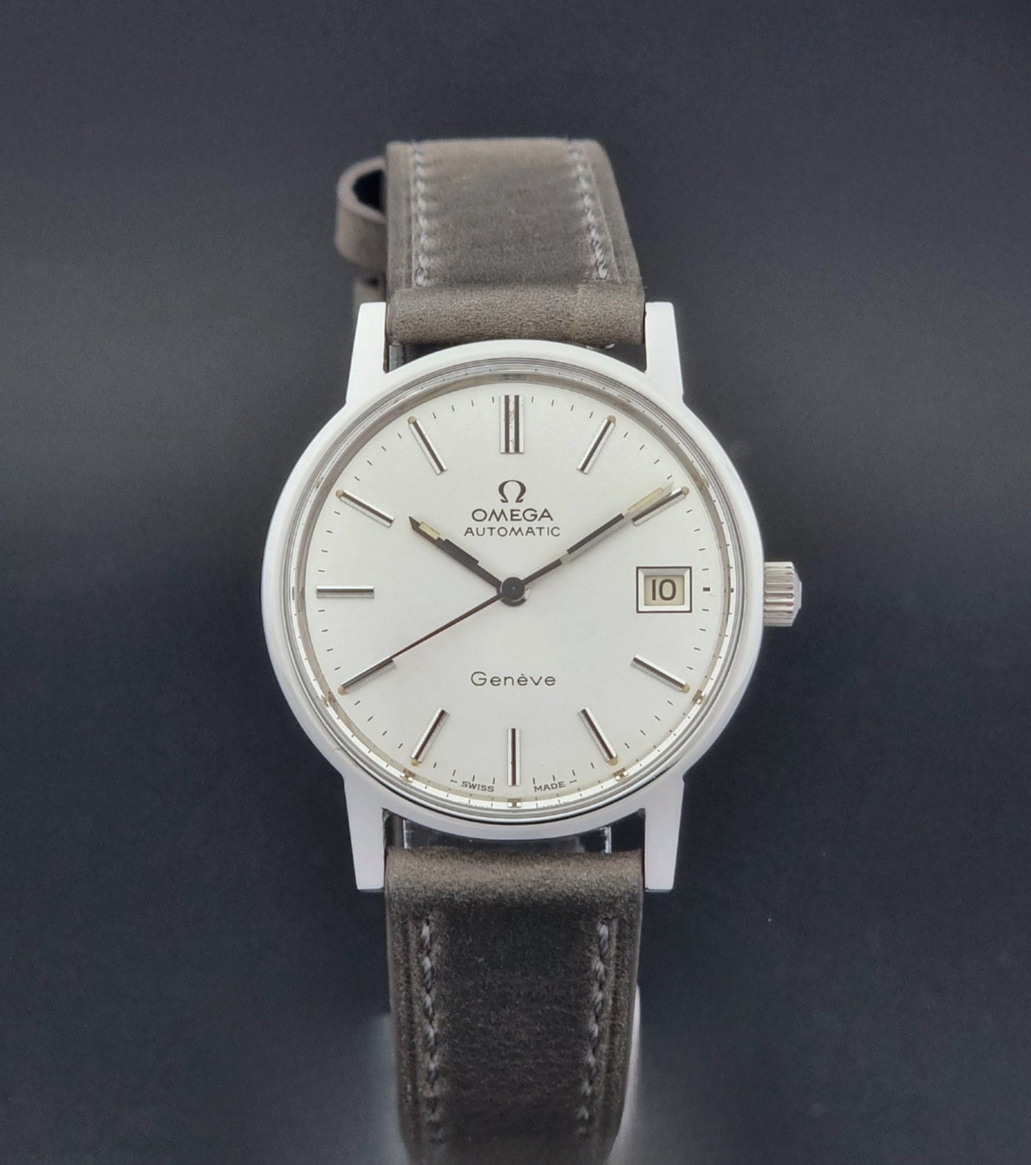 Vintage Omega Geneve 166.0163 watch with gray leather strap on a dark background close dial view