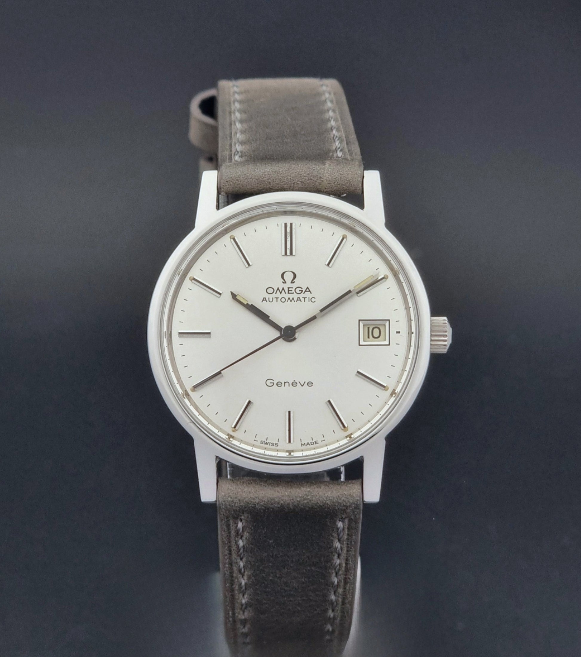 Vintage Omega Geneve 166.0163 watch with gray leather strap on a dark background close dial view