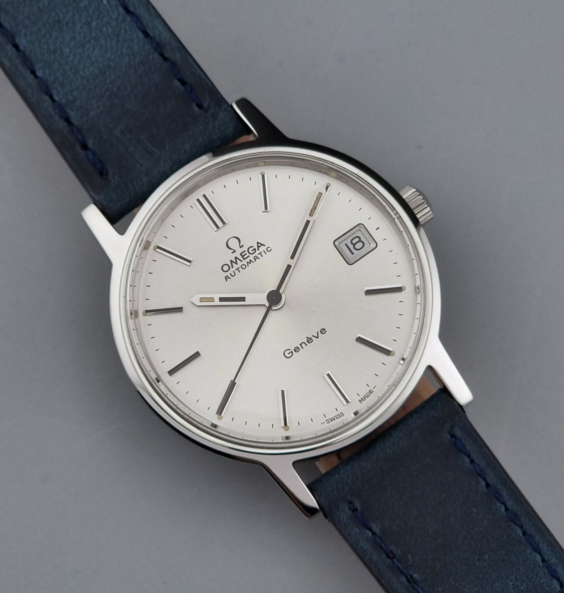 Vintage Omega Geneve 166.0163 wristwatch with blue leather strap on a gray background
