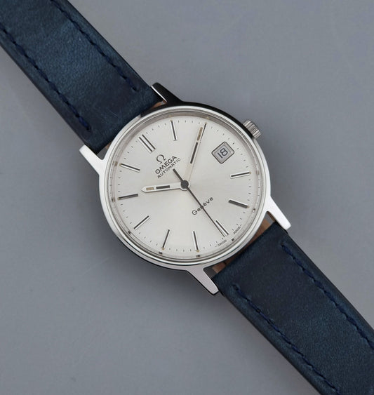 Vintage Omega Geneve 166.0163 wristwatch with a blue leather strap on a gray background