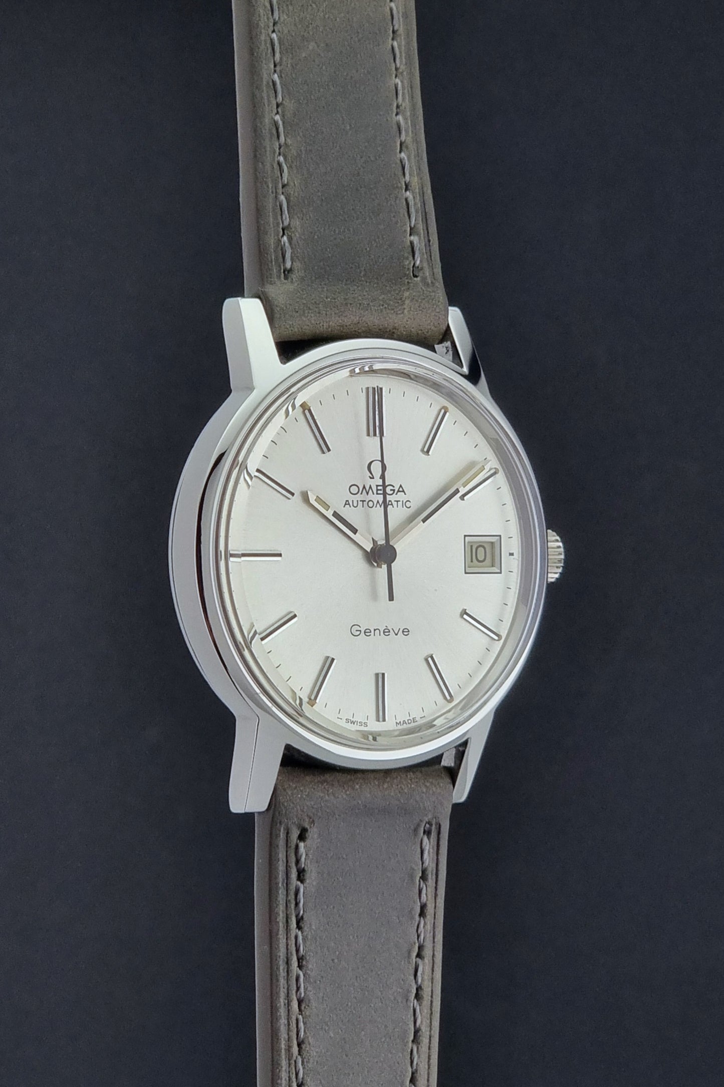 Vintage Omega Geneve 166.0163 watch with gray leather strap on a dark background side view