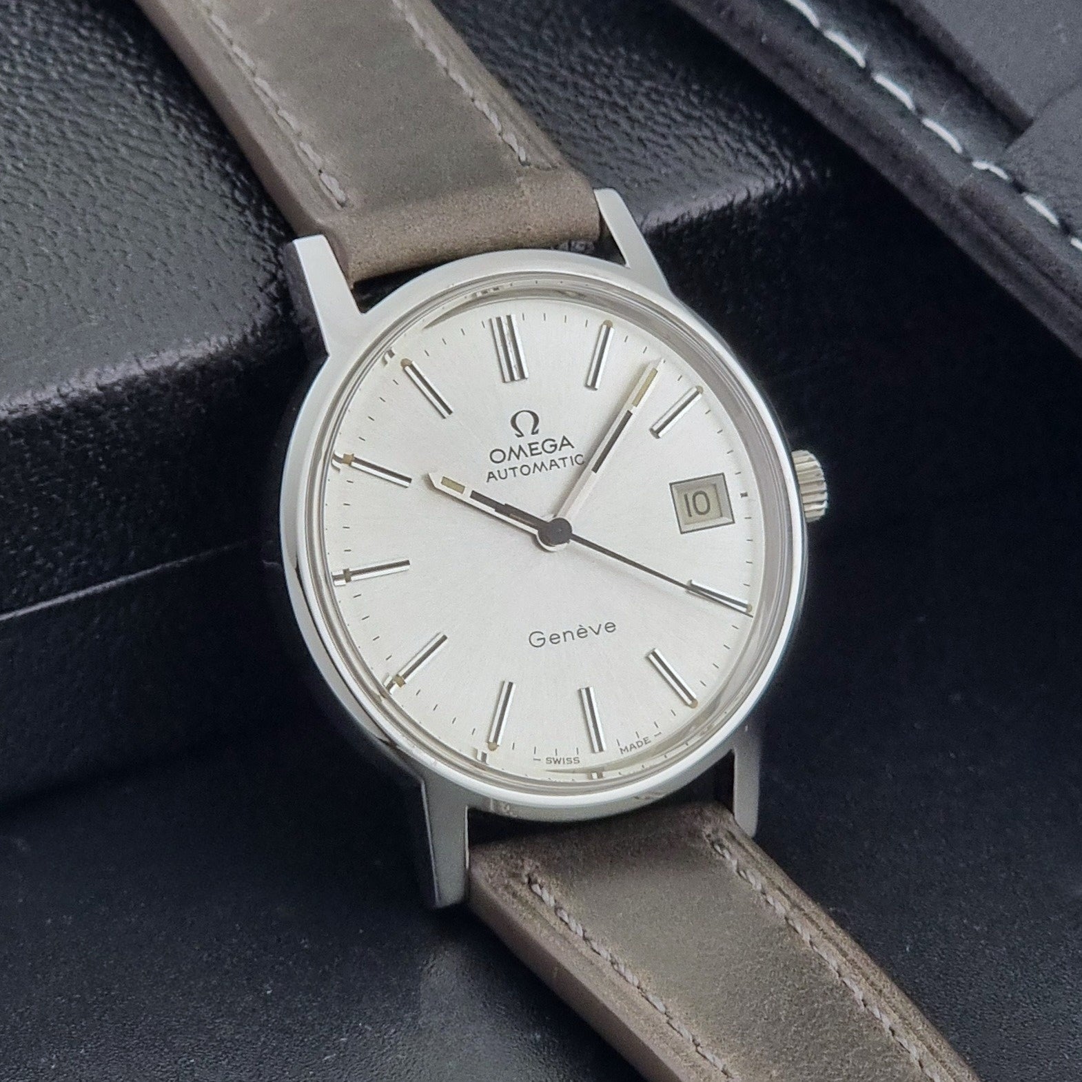Vintage Omega Geneve 166.0163 watch with gray leather strap on a dark background side view