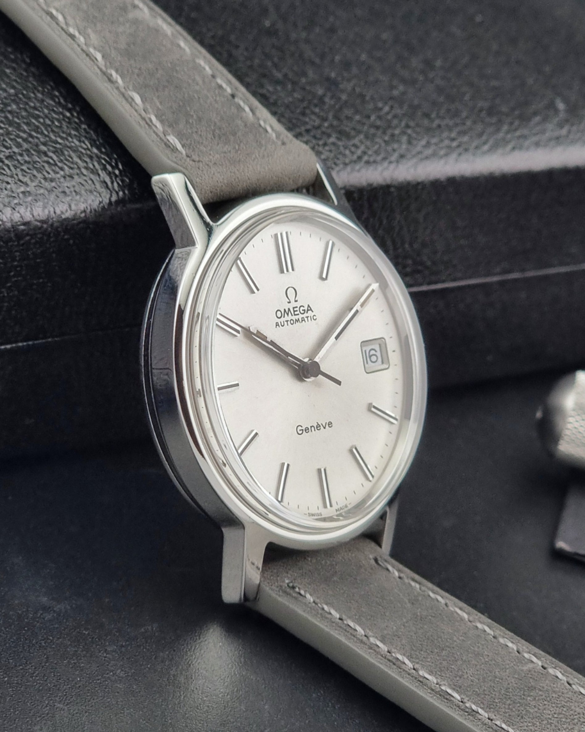 Vintage Omega watch with a silver case and white dial on a dark background