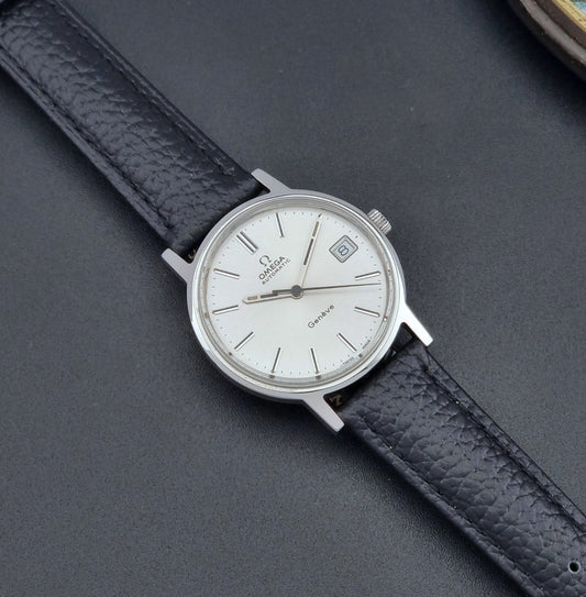 Vintage Omega Geneve Wristwatch 166.0163 with black leather strap and silver case on a dark gray background dial