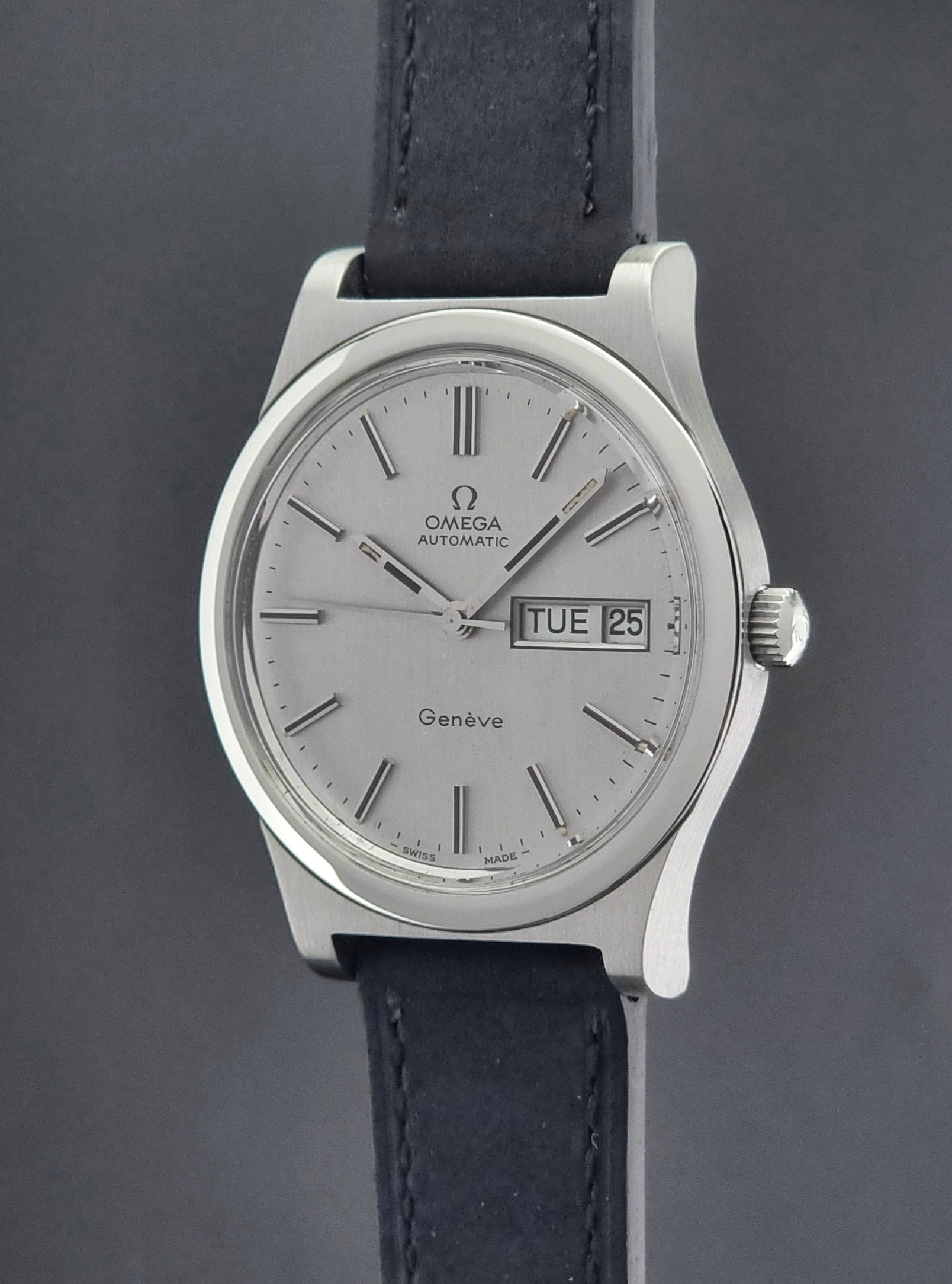 Vintage Omega Geneve 166.0169 wristwatch with a black strap on a dark background crown profile view