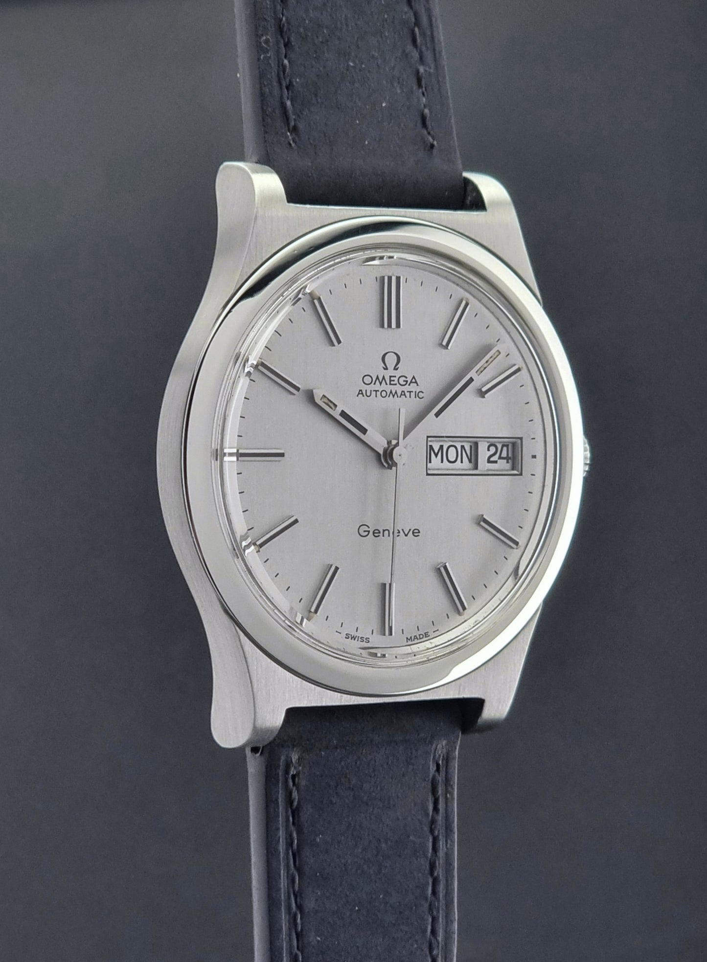 Vintage Omega Geneve 166.0169 wristwatch with a black strap on a dark background side profile view