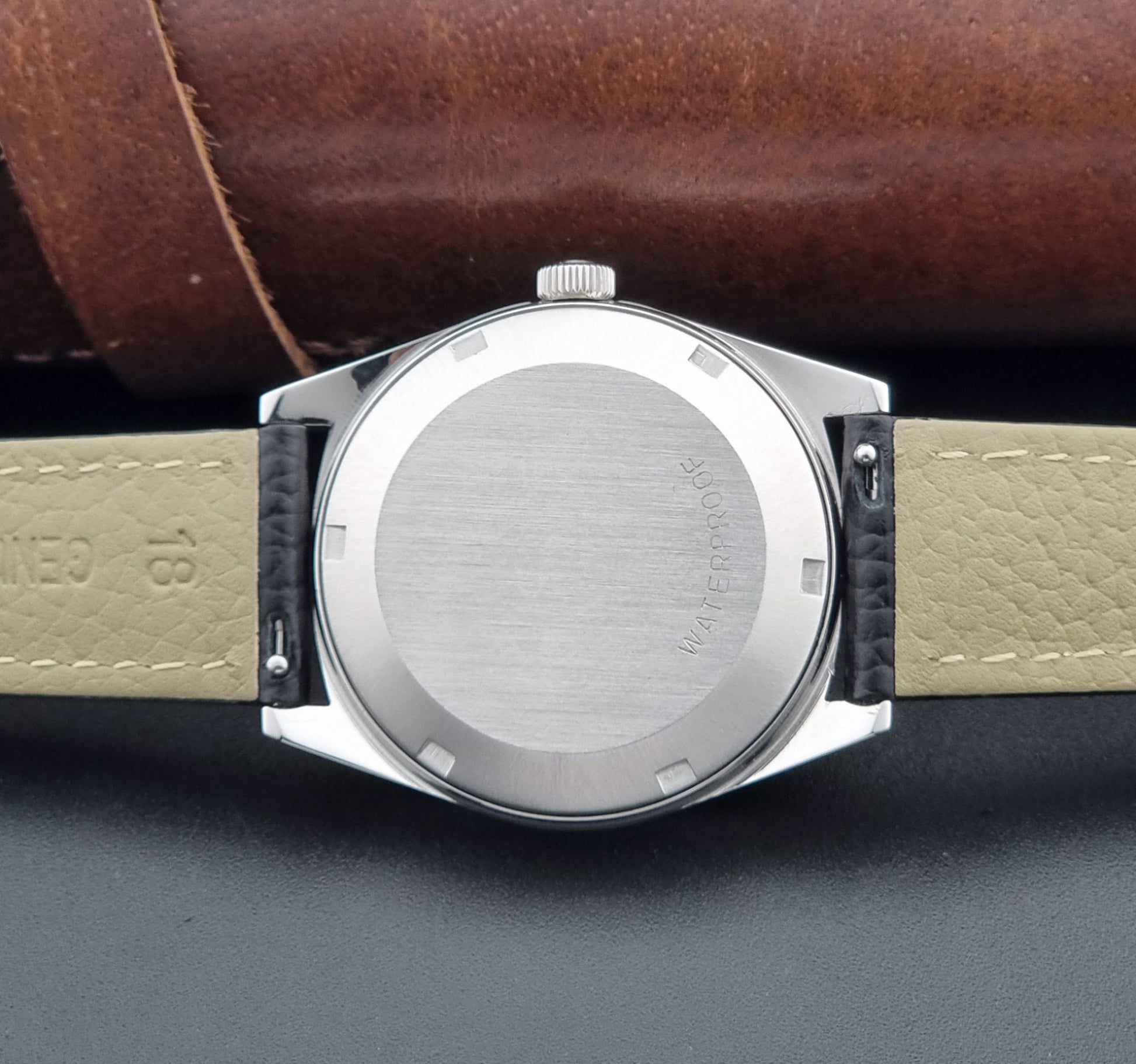 Vintage Omega Wristwatch a Geneve 166.041 with black leather strap on a dark surface case back view