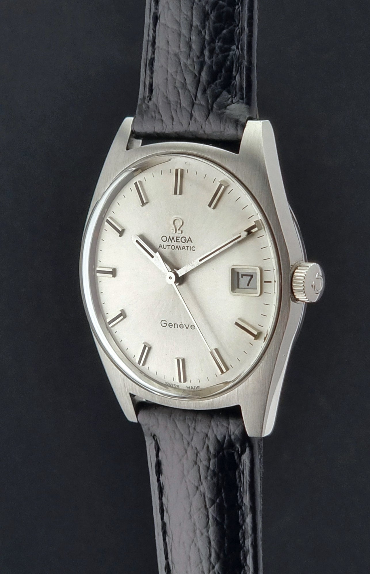 Vintage Omega Wristwatch a Geneve 166.041 with black leather strap on a dark surface crown profile view