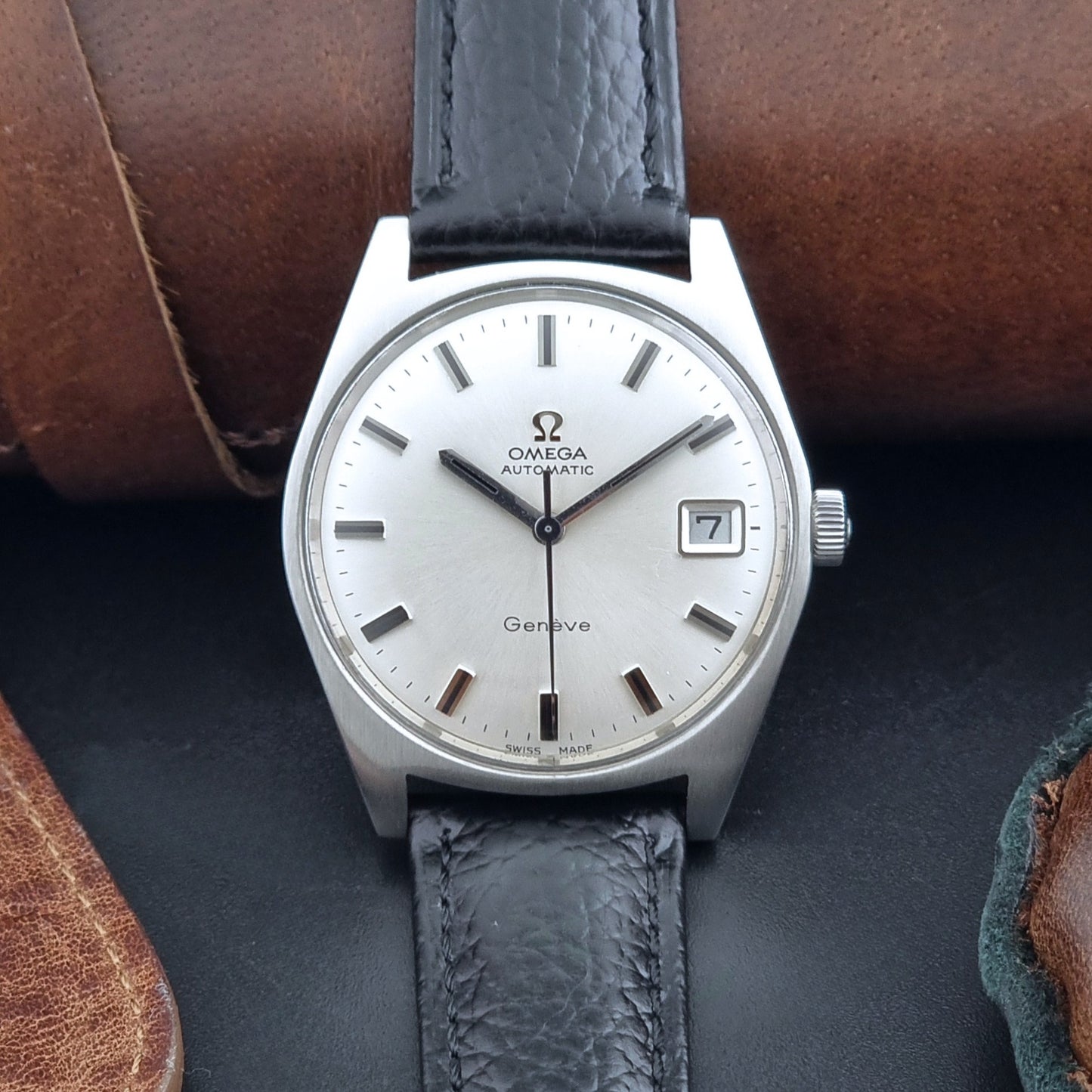 Vintage Omega Wristwatch a Geneve 166.041 with black leather strap on a dark surface dial view