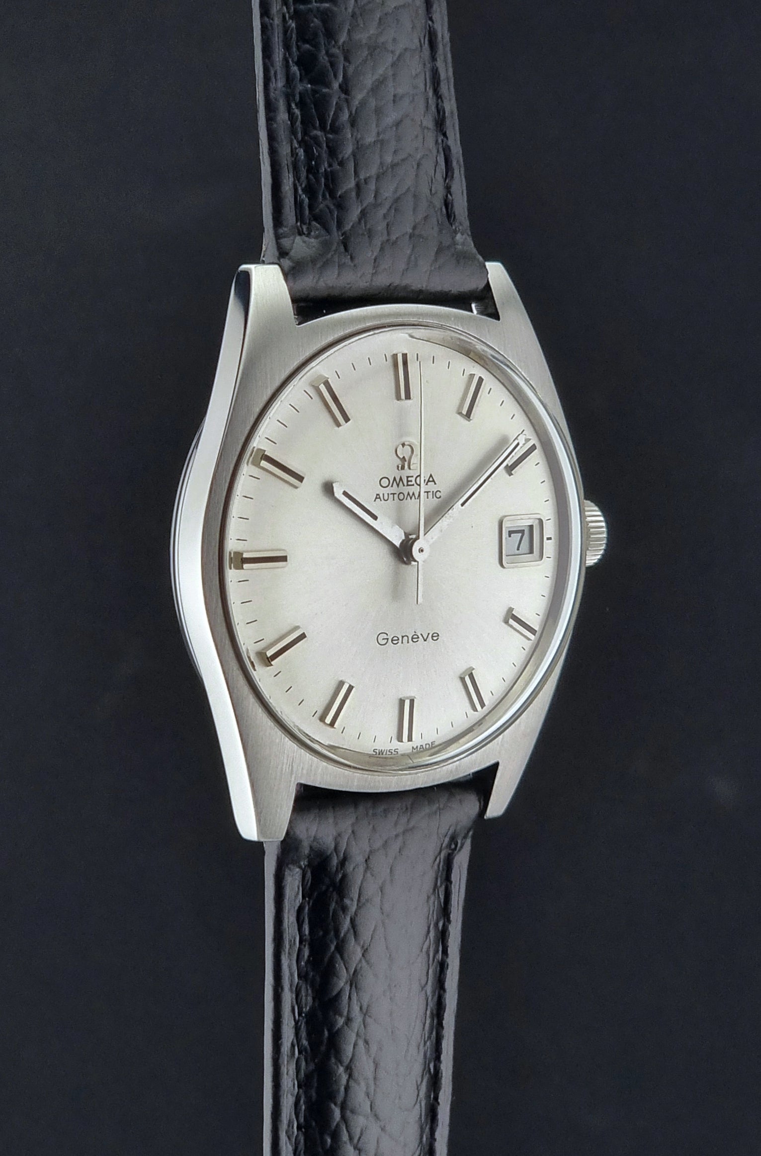 Vintage Omega Wristwatch a Geneve 166.041 with black leather strap on a dark surface side profile view