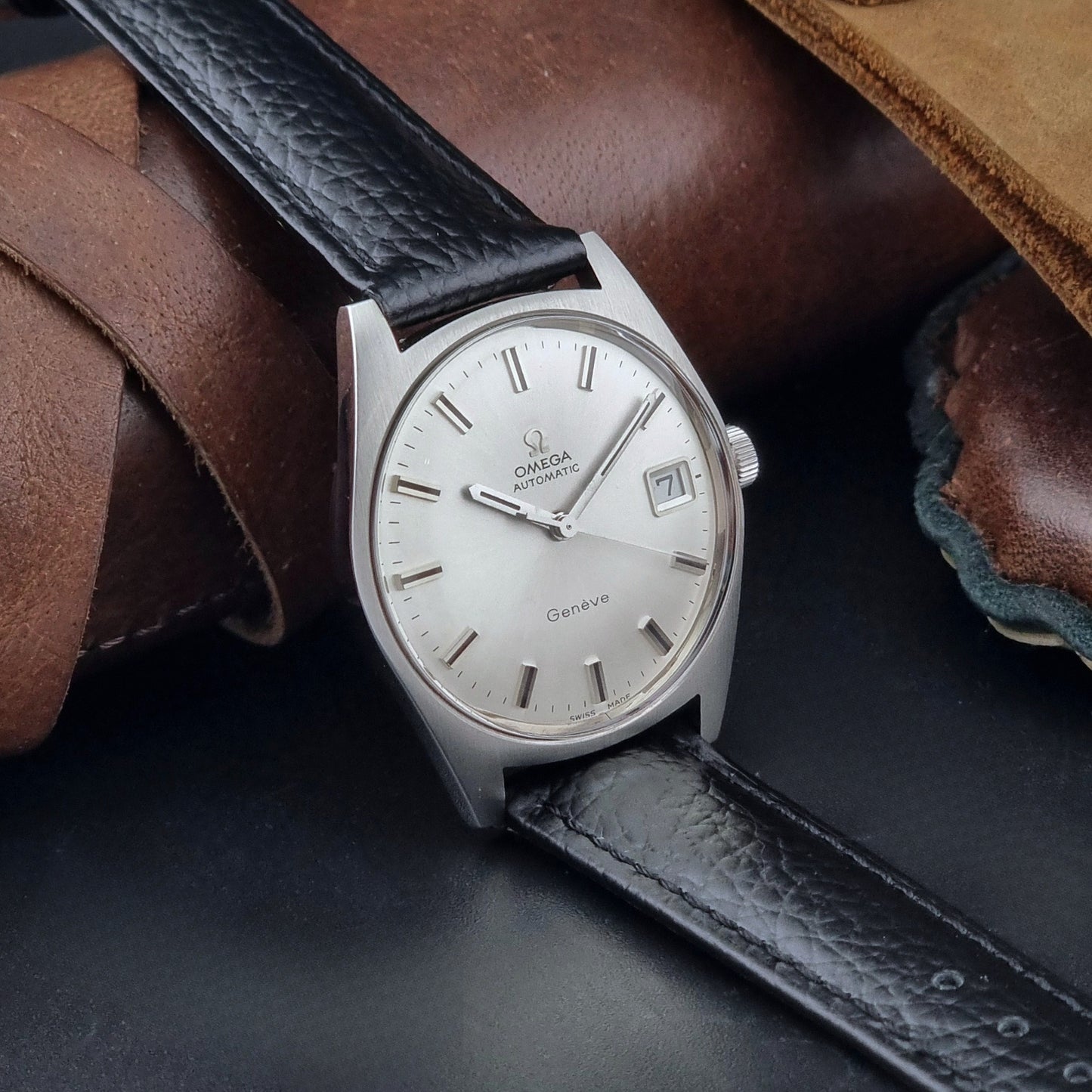 Vintage Omega Wristwatch a Geneve 166.041 with black leather strap on a dark surface side view