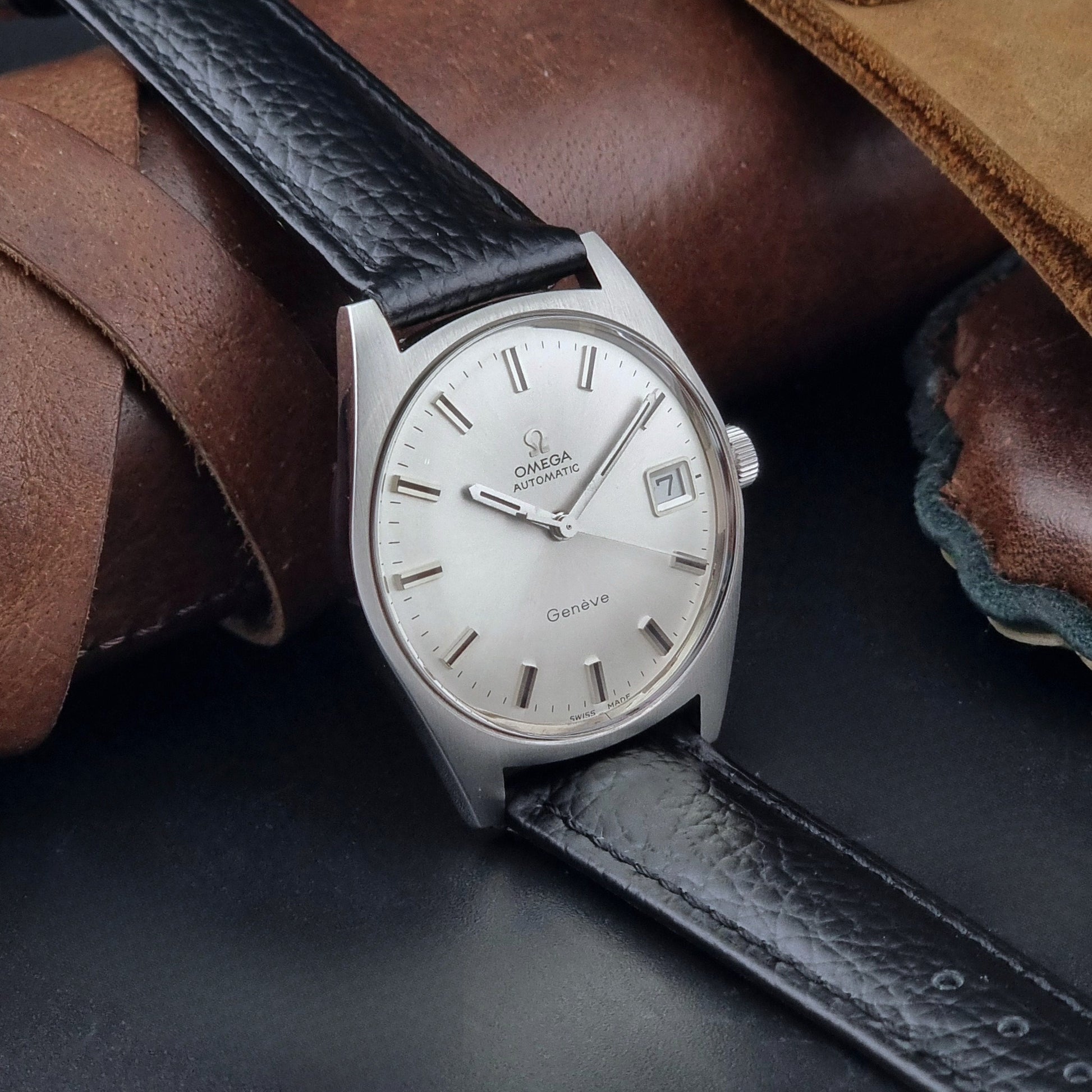 Vintage Omega Wristwatch a Geneve 166.041 with black leather strap on a dark surface side view