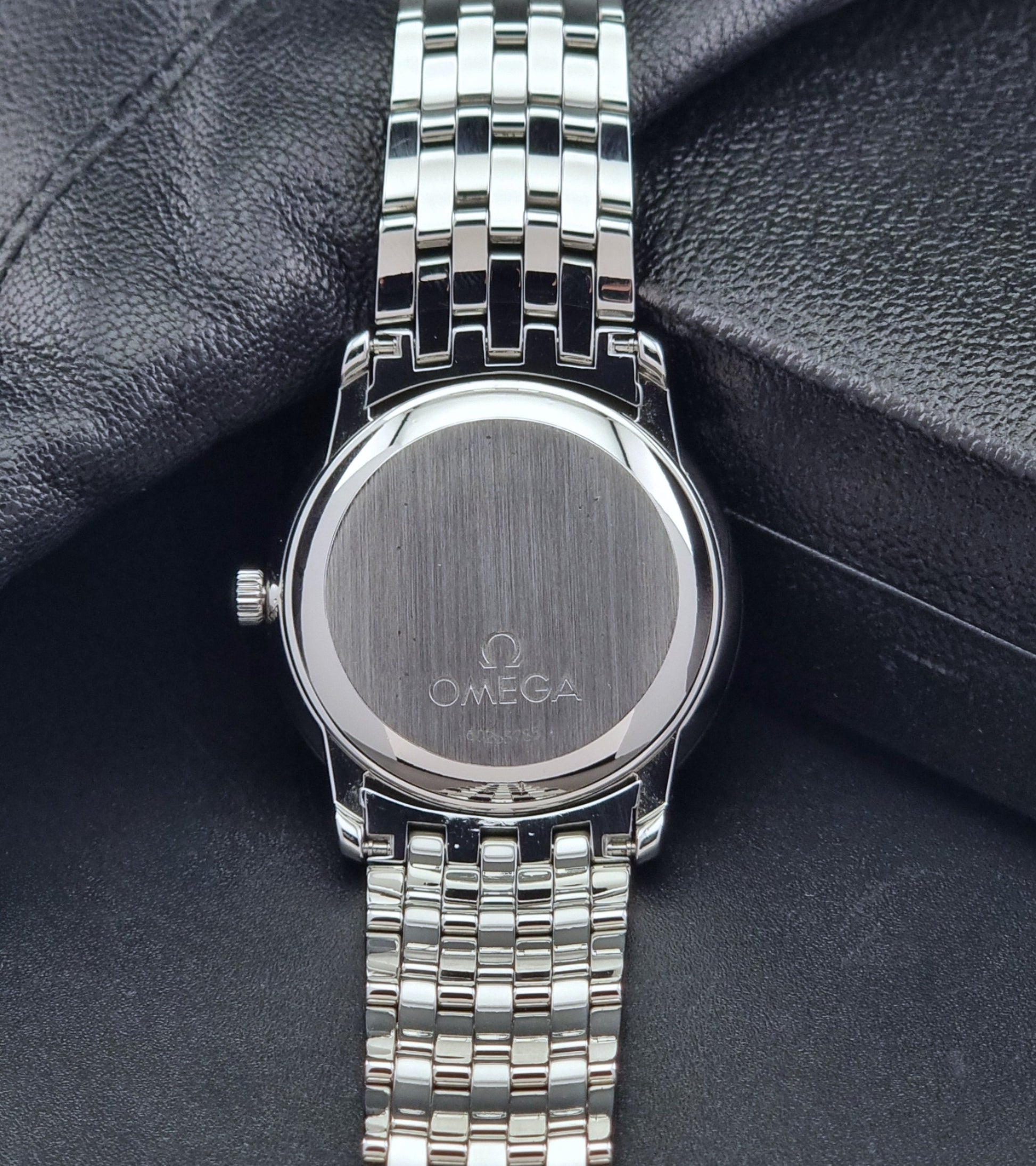 Omega watch a De-Ville Prestige 168.1050 with a stainless steel bracelet on a dark background case back view