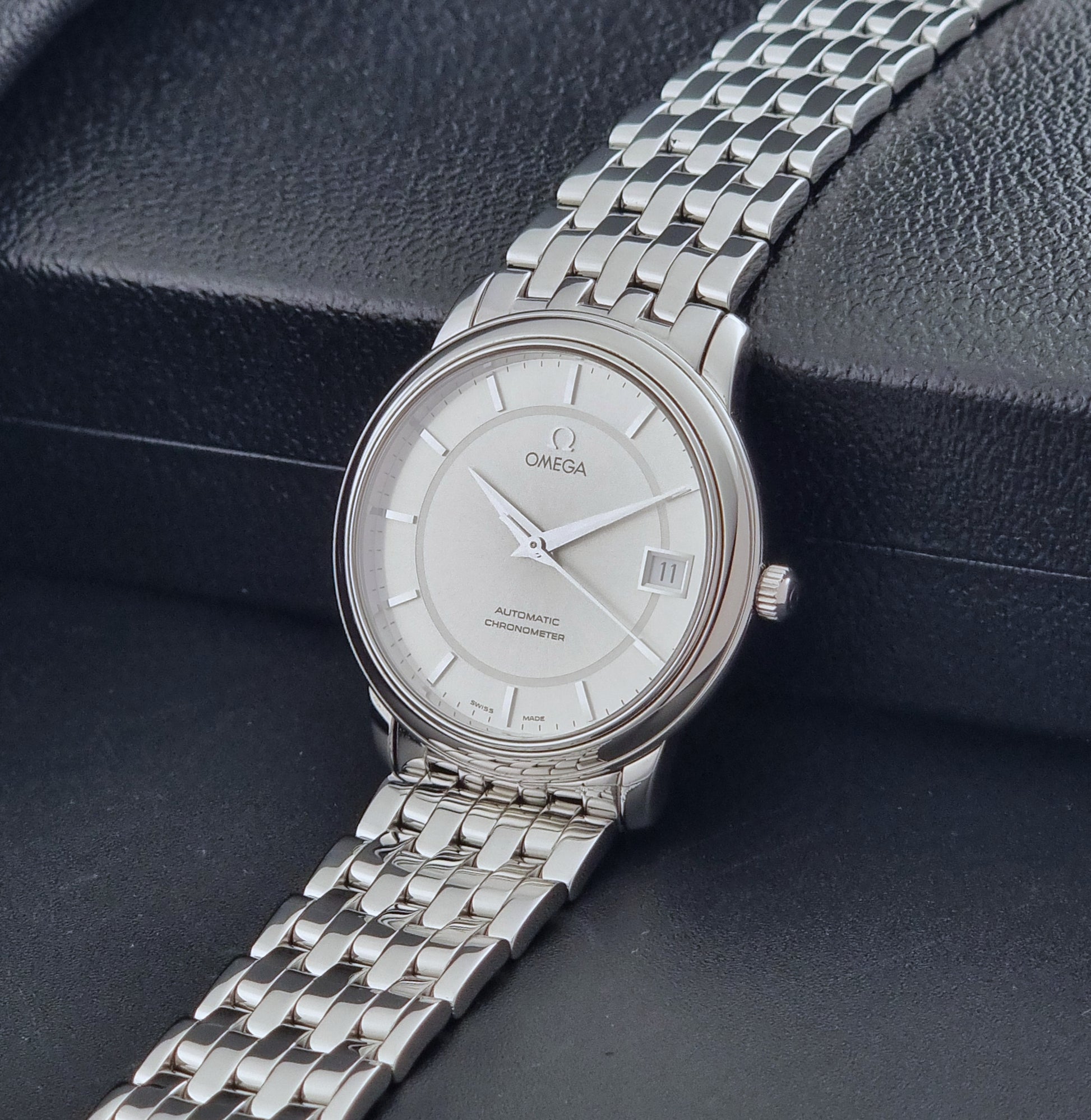 Omega watch a De-Ville Prestige 168.1050 with a stainless steel bracelet on a dark background crown view