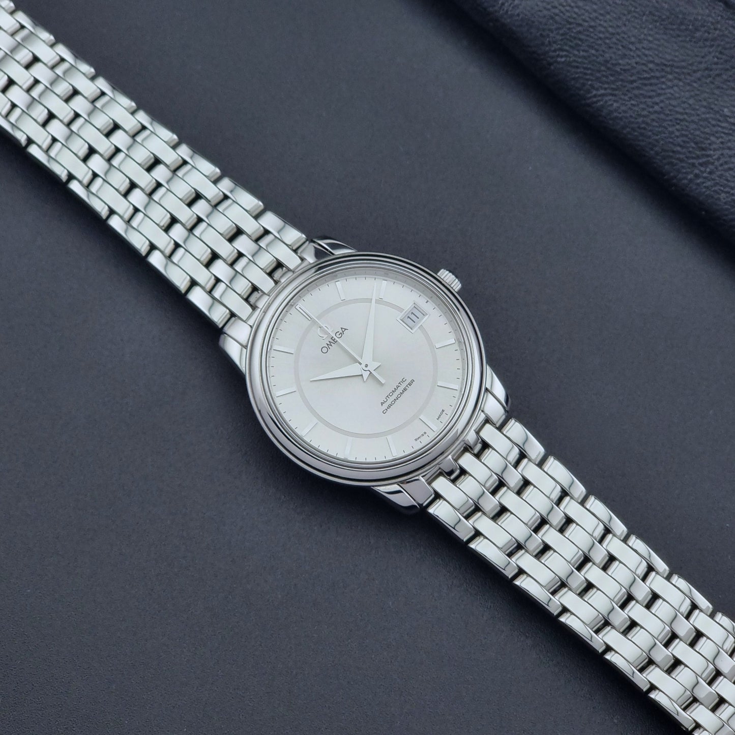 Omega watch a De-Ville Prestige 168.1050 with a stainless steel bracelet on a dark background dial
