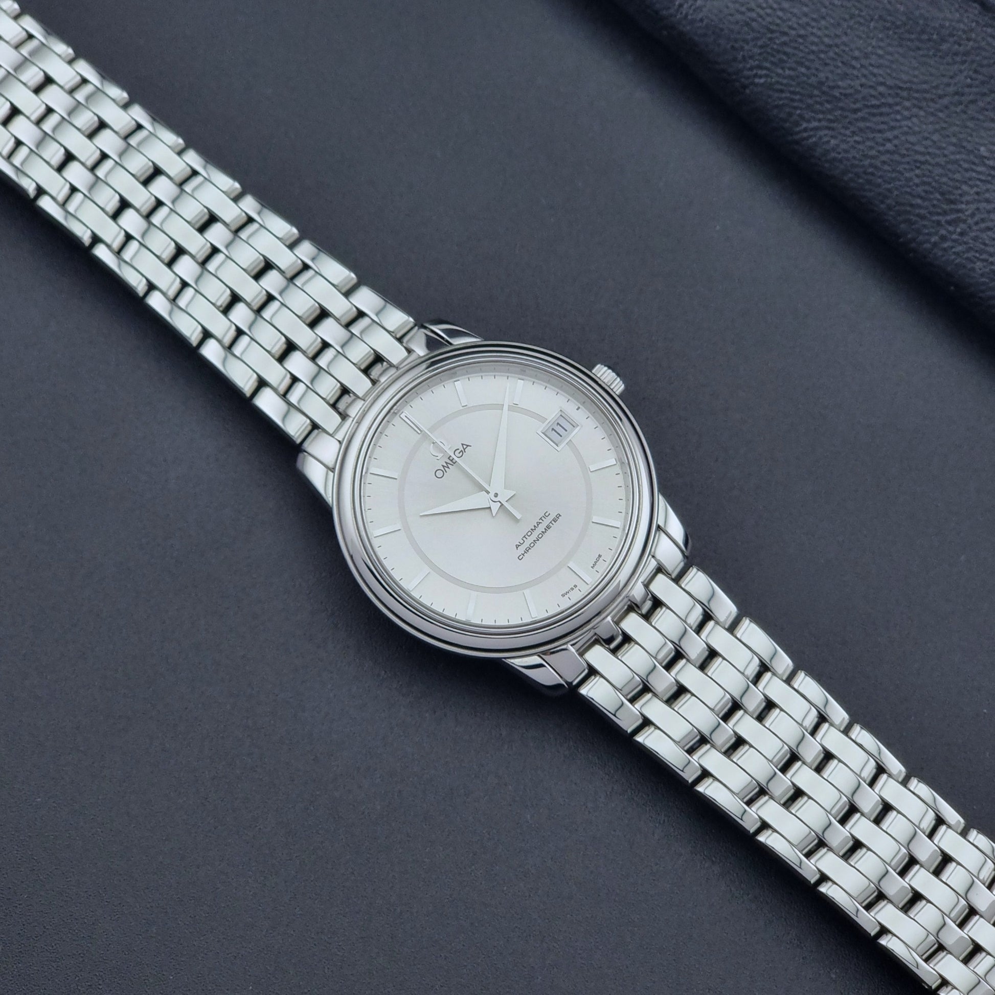 Omega watch a De-Ville Prestige 168.1050 with a stainless steel bracelet on a dark background dial